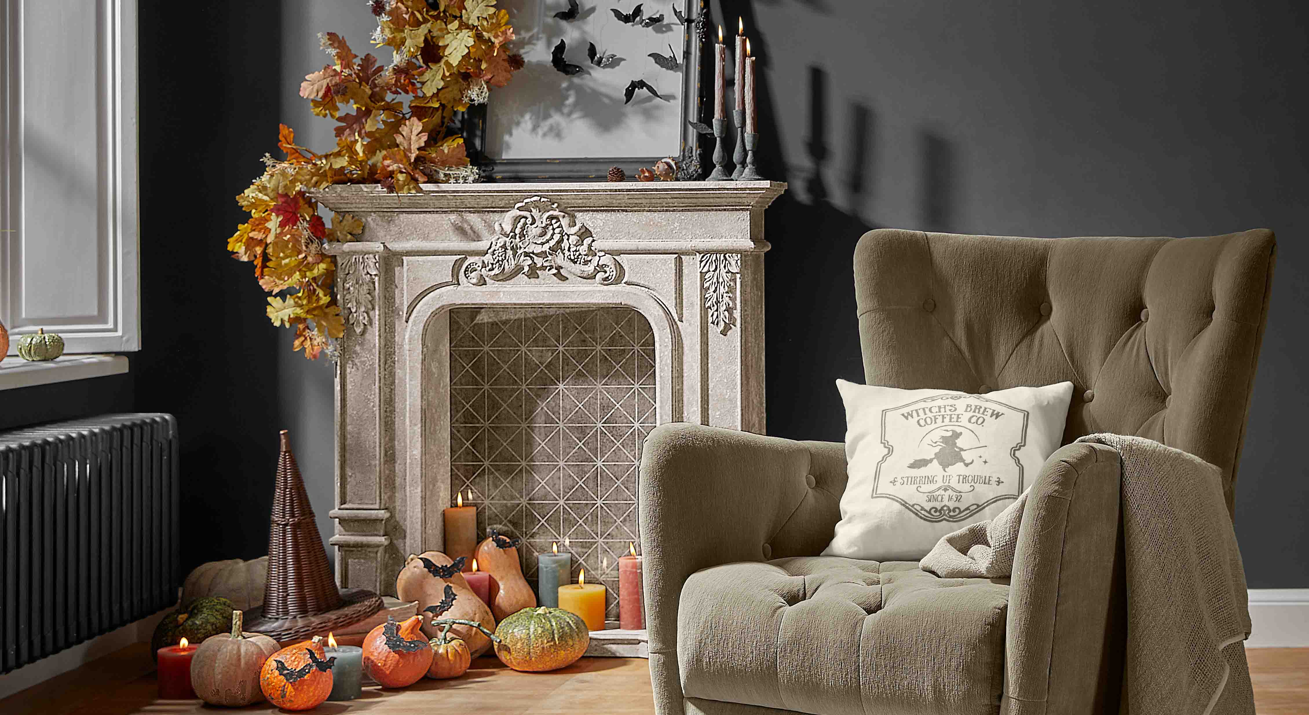 Chimenea decorativa con hojas otoñales, calabazas y velas en salón acogedor con sillón beige