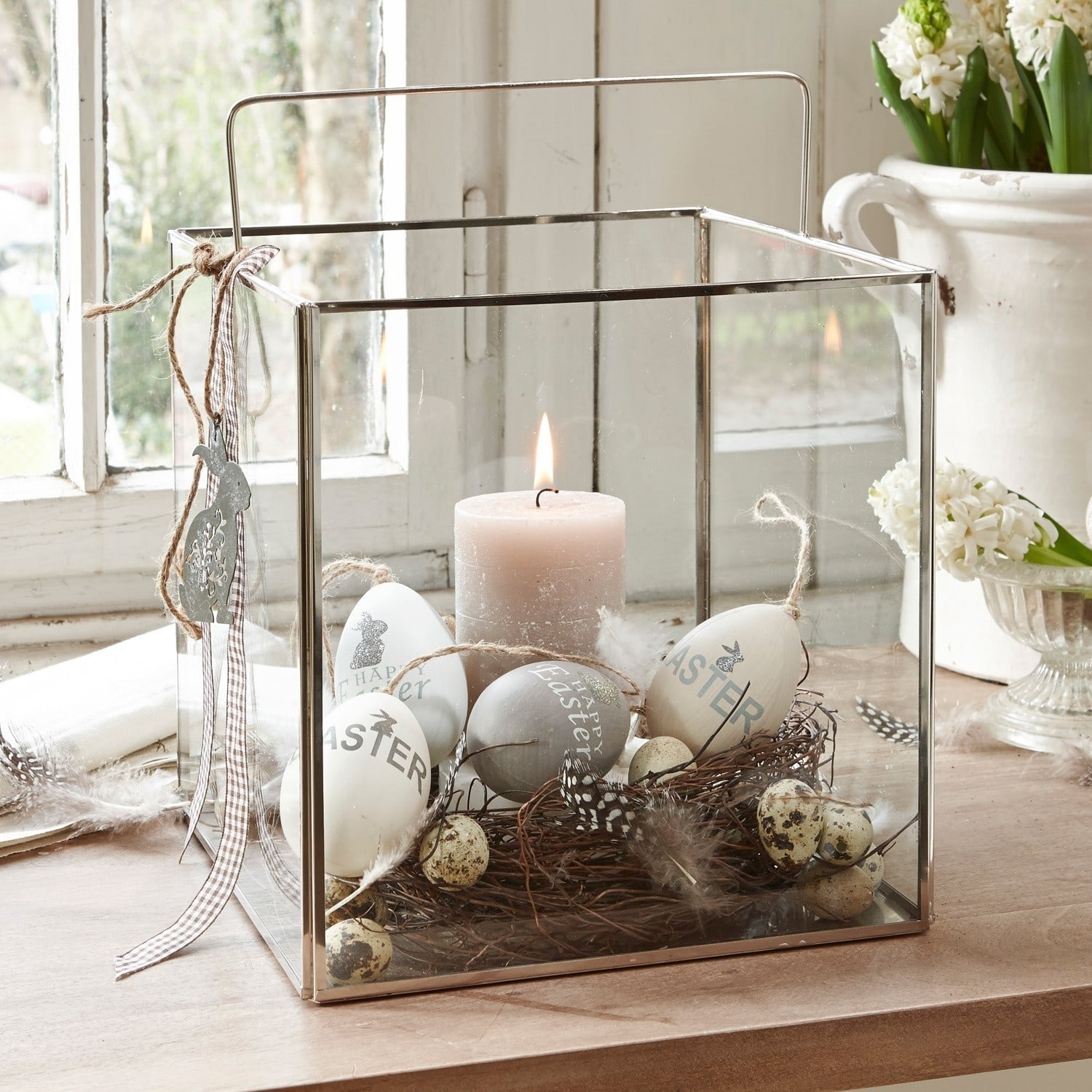 Farolillo Otero Linterna de vidrio con marco metálico, decorada con huevos de Pascua y vela sobre mesa de madera