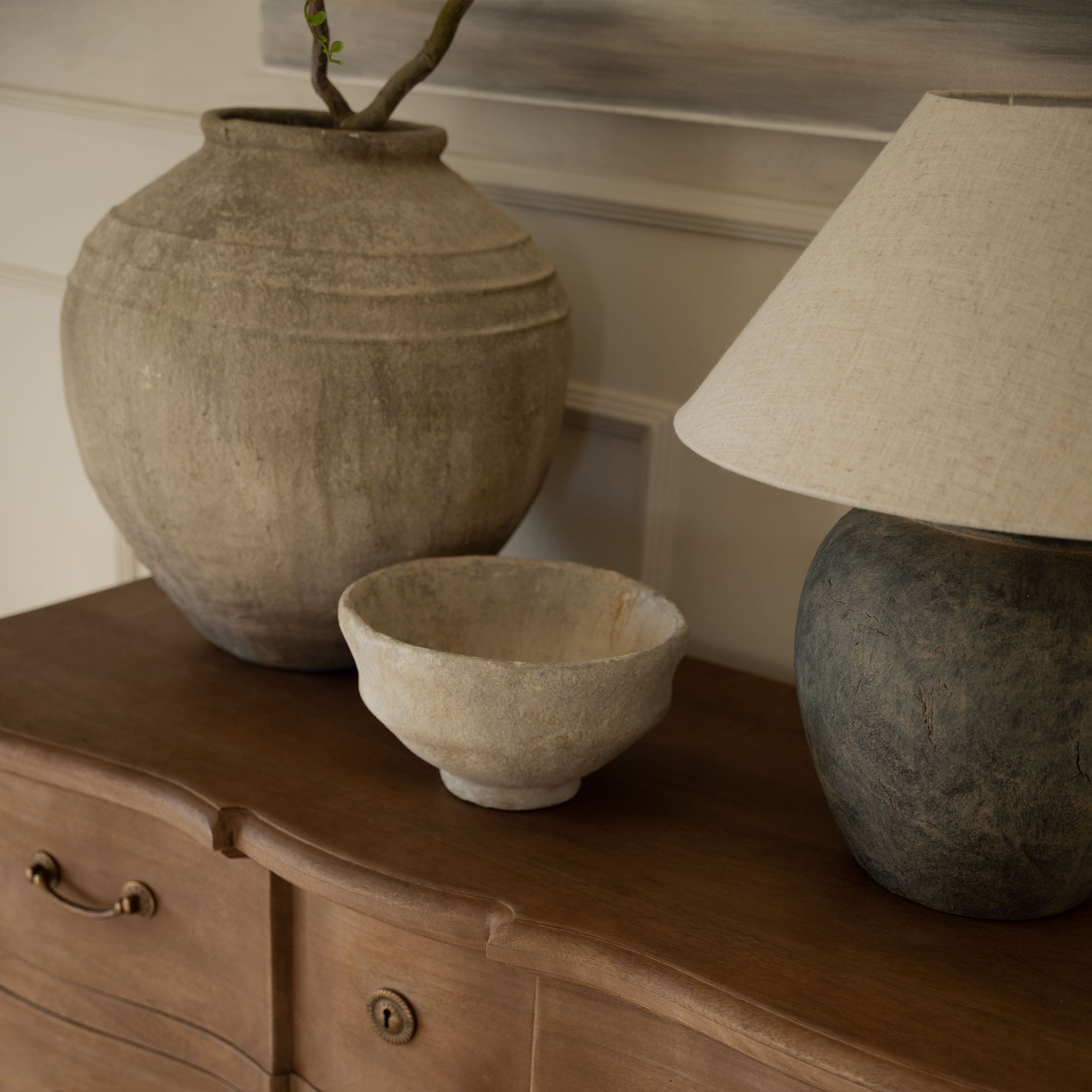 Jarrones y cuenco decorativos de cerámica en tonos naturales sobre cómoda de madera