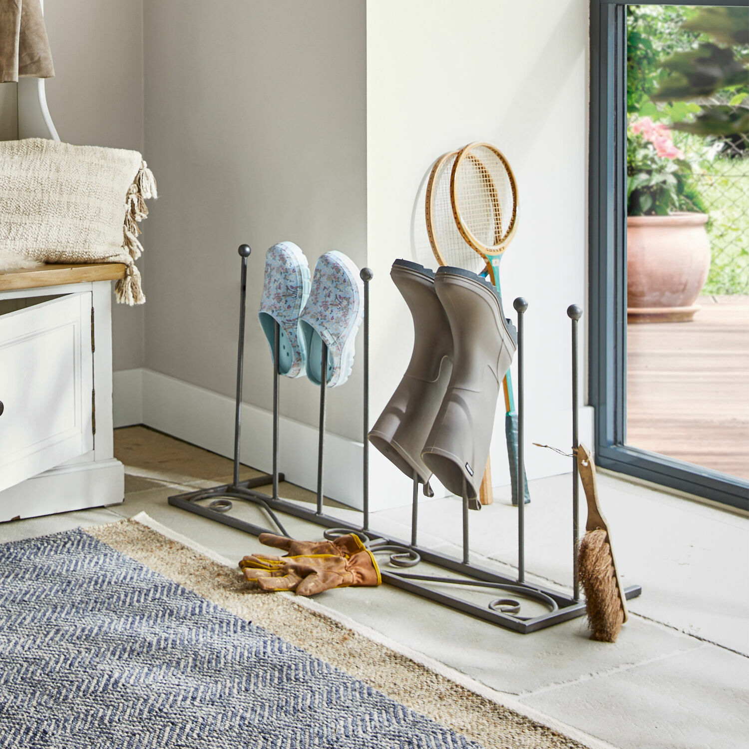 Zapatero Patterson Soporte metálico para zapatos con botas grises y zuecos florales en interior luminoso