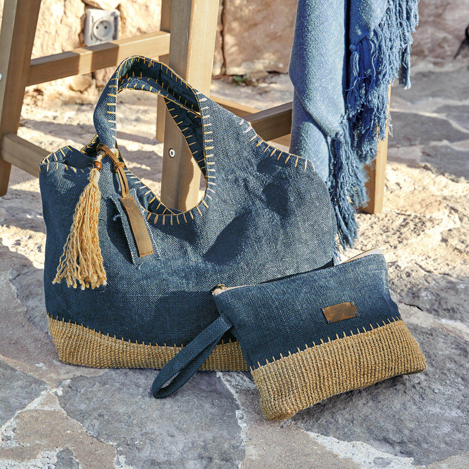Set de 2 bolsos Cacula Bolso y neceser azul marino de material natural con detalles beige sobre suelo de piedra
