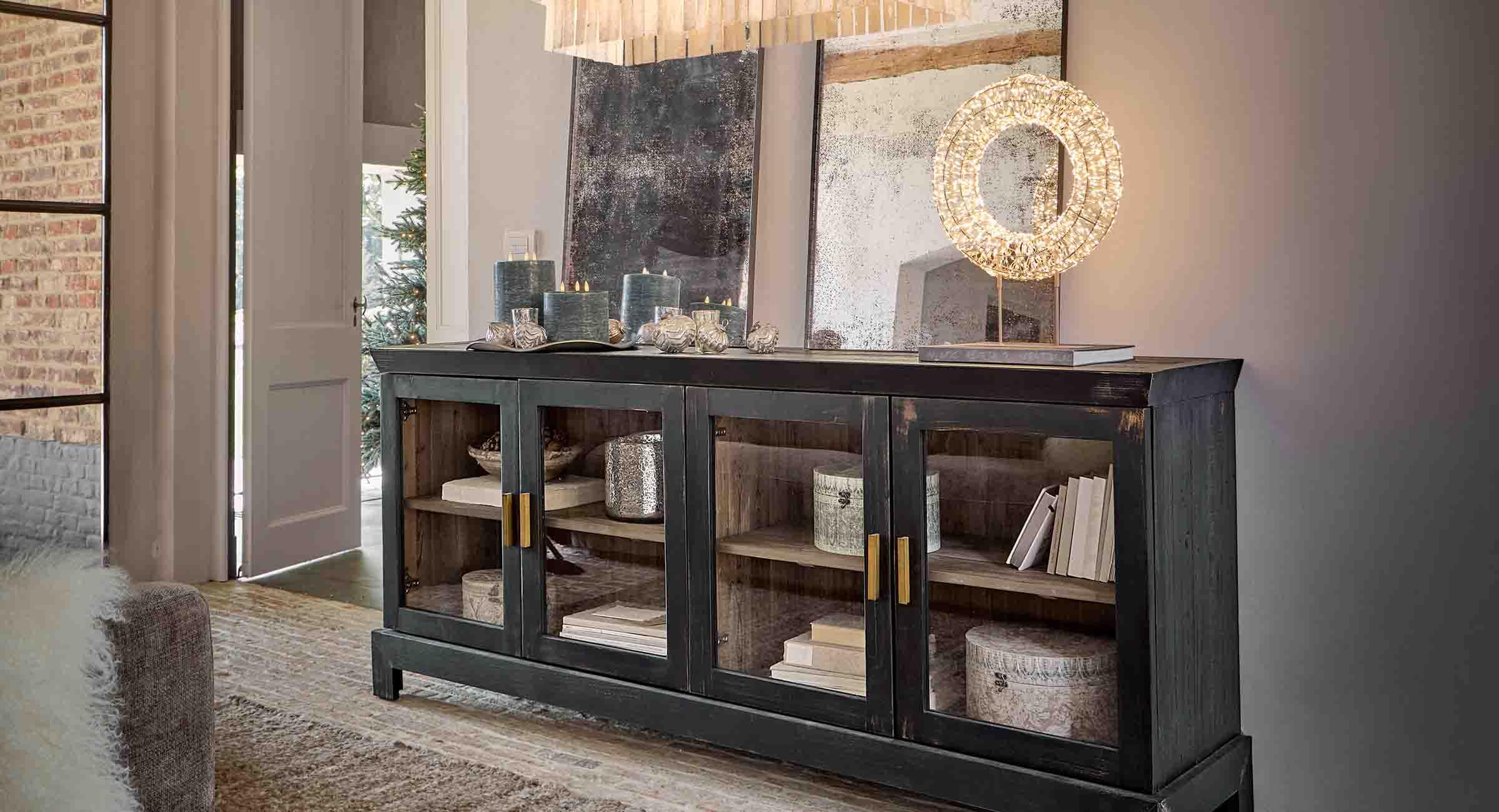 Aparador de madera negra con puertas de cristal y velas decorativas en salón elegante