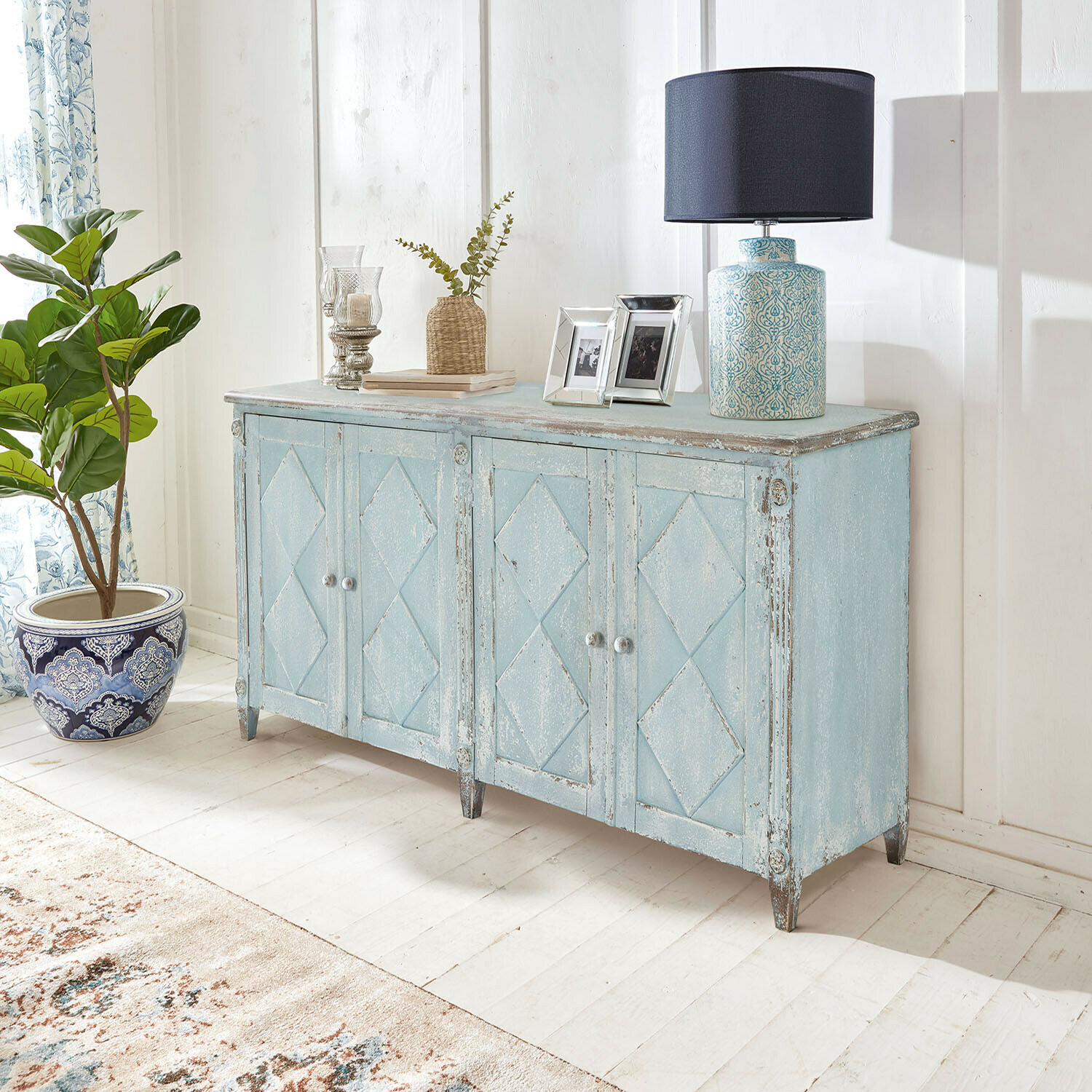 Cómoda Resplandor Aparador de madera azul envejecida con lámpara de mesa decorativa en estilo vintage en interior luminoso