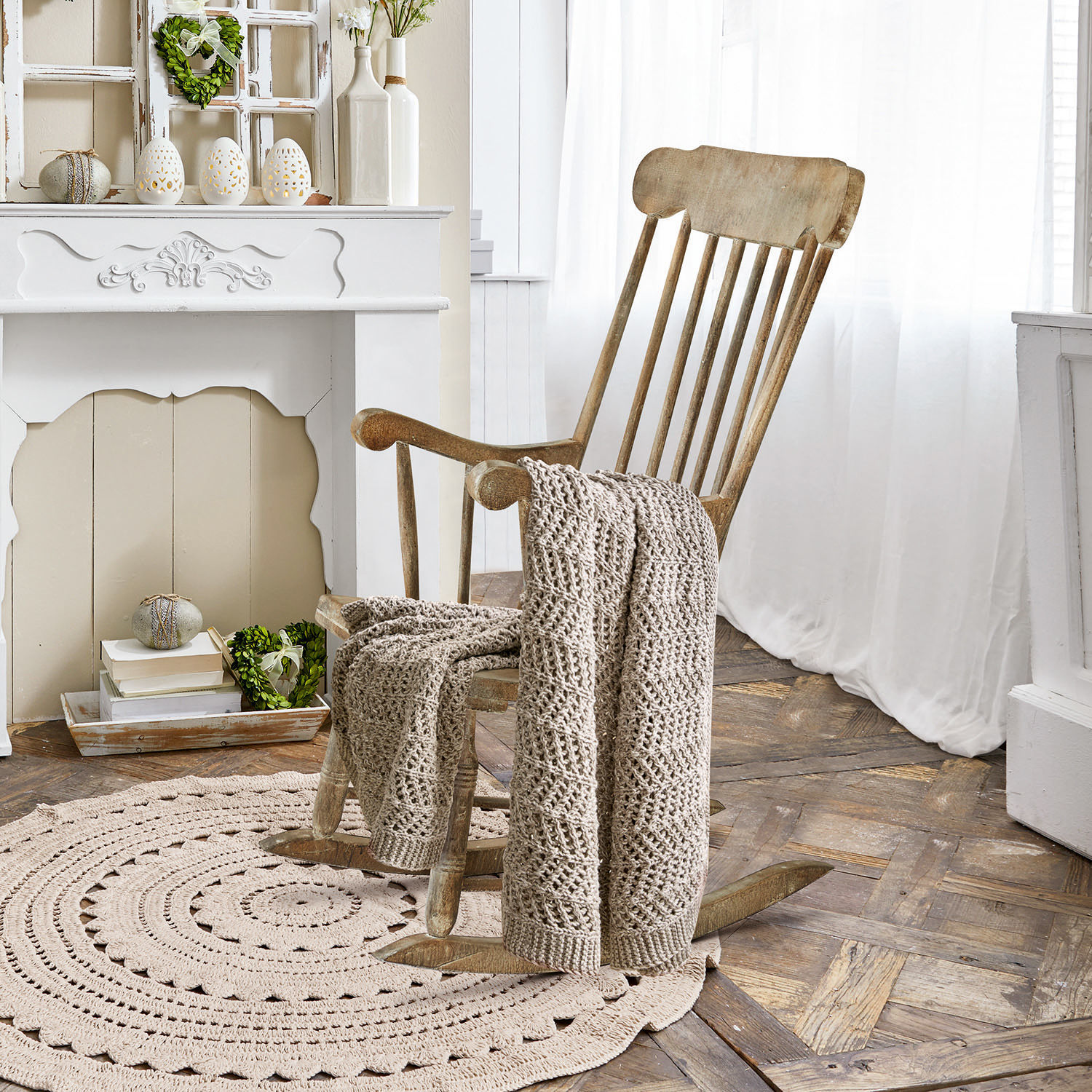Mecedora Adaleine Sillón mecedor de madera con manta beige tejida sobre alfombra redonda en habitación luminosa
