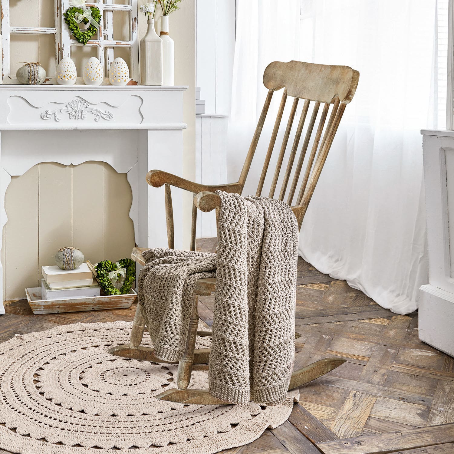 Mecedora Adaleine Sillón mecedor de madera con manta beige tejida sobre alfombra redonda en habitación luminosa