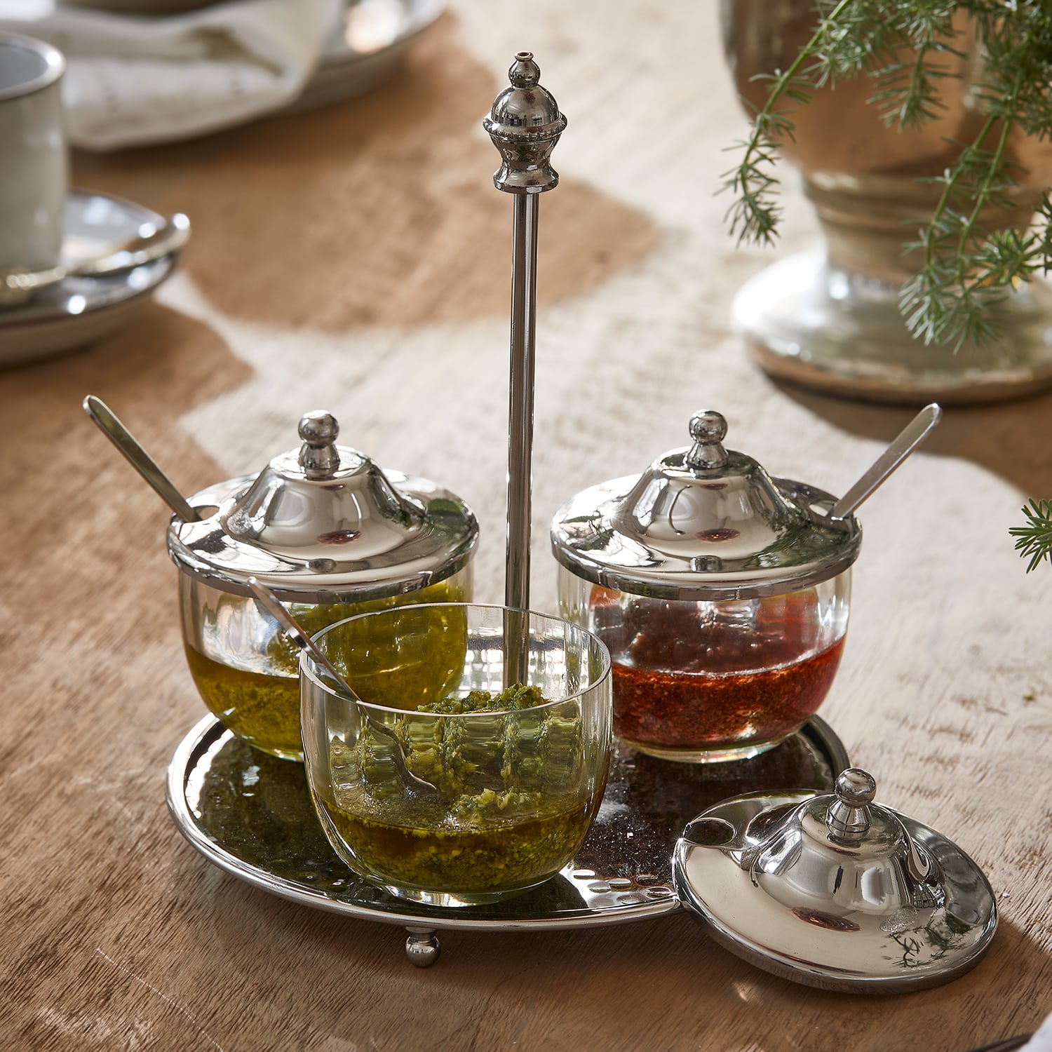 Conjunto de recipientes de vidrio para especias con tapas metálicas sobre bandeja metálica en mesa de madera