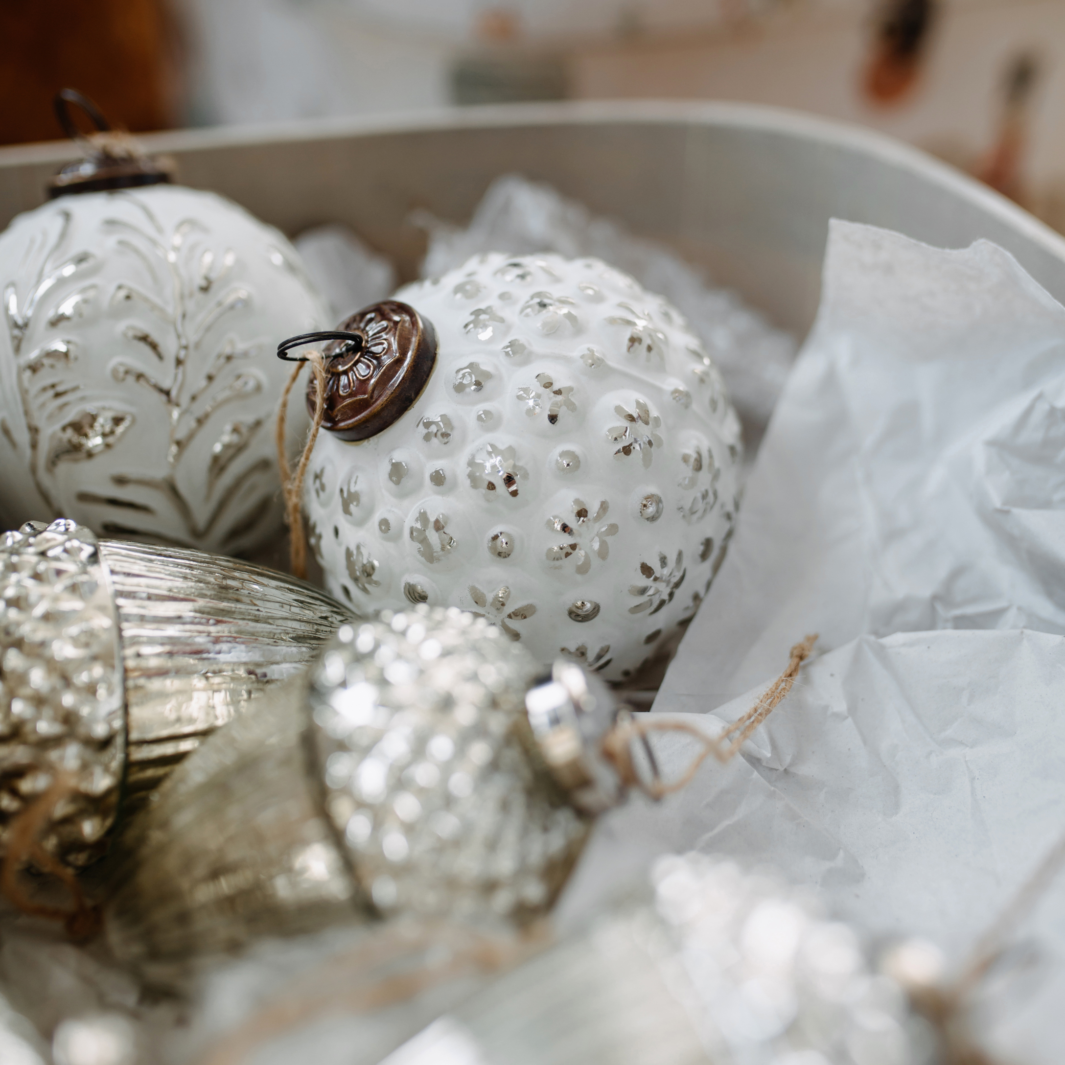 Bolas de Navidad blancas y plateadas de vidrio y metal con patrones, en caja con papel