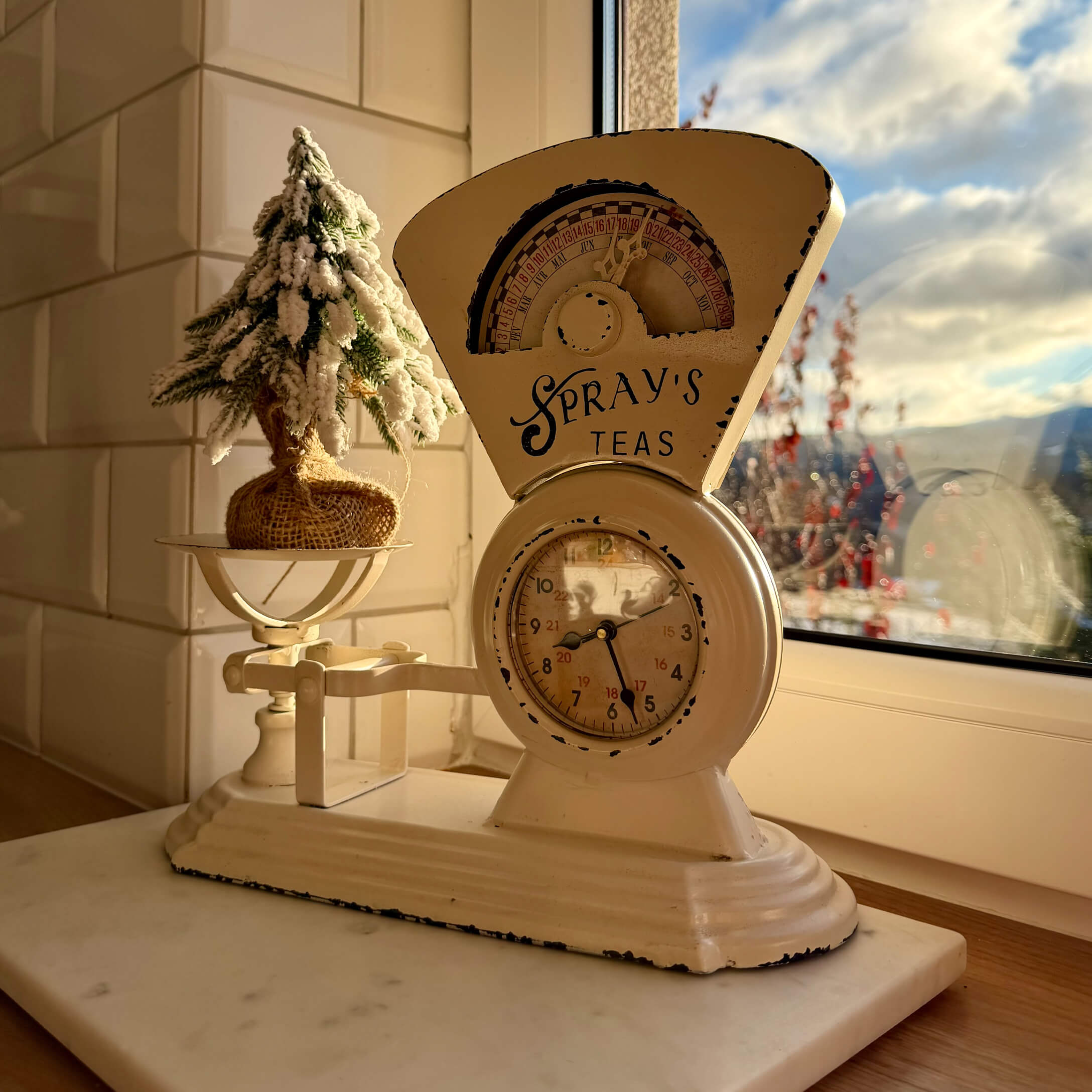 Báscula de cocina metálica beige con reloj y decoración navideña en el alféizar de la ventana