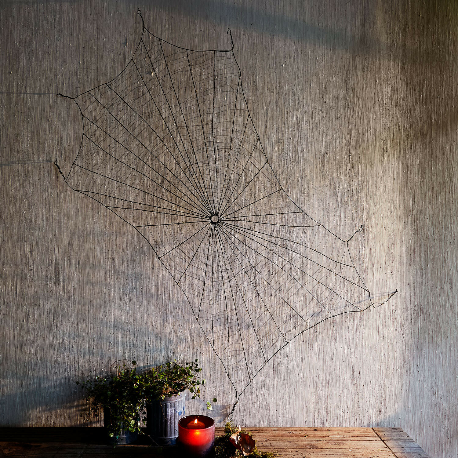 Telaraña decorativa Vexilnor Decoración de pared con telaraña metálica negra, vela roja y planta sobre mesa de madera
