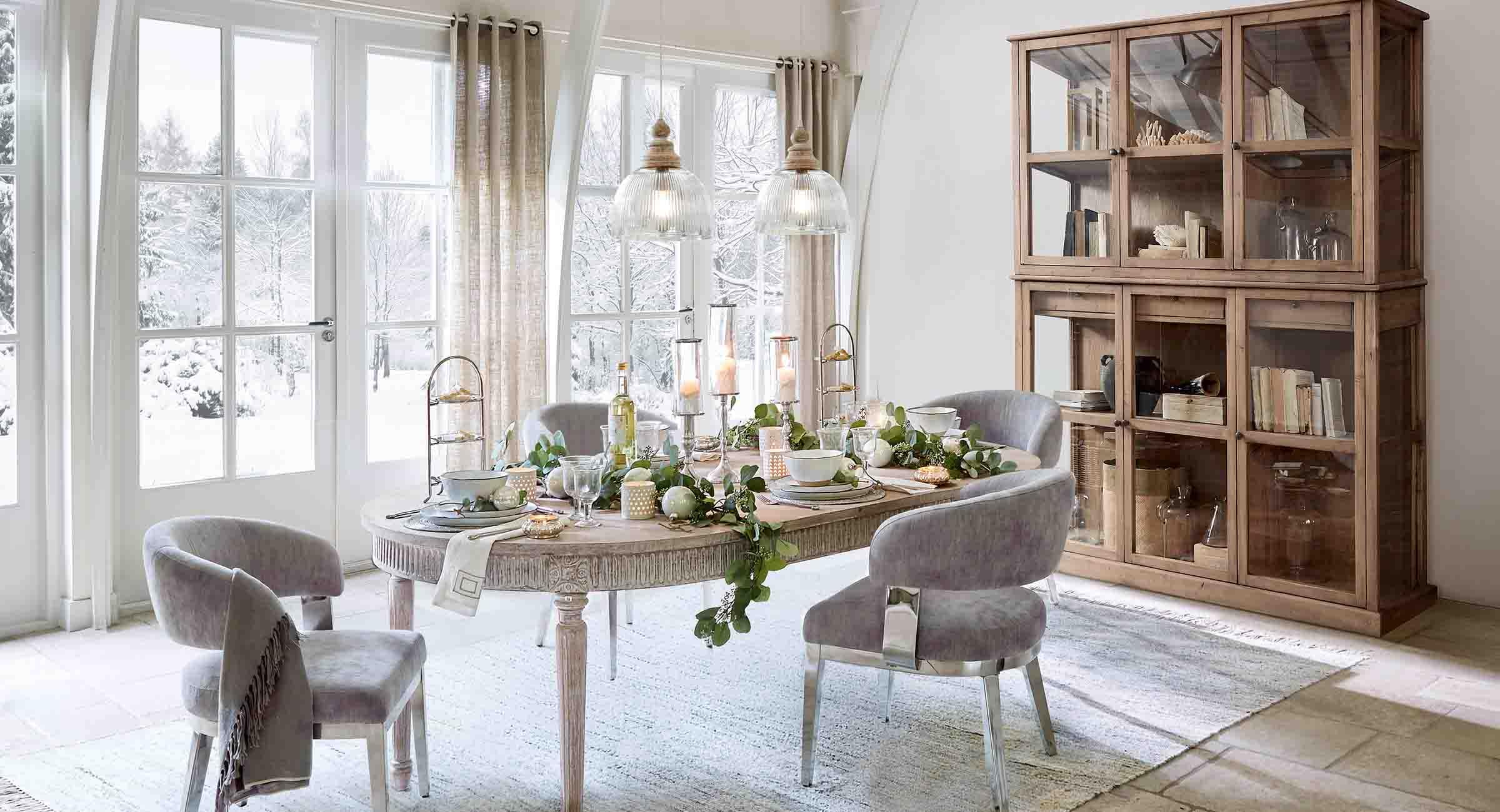 Comedor con mesa de madera y sillas grises decorado para invierno con vista a jardín nevado
