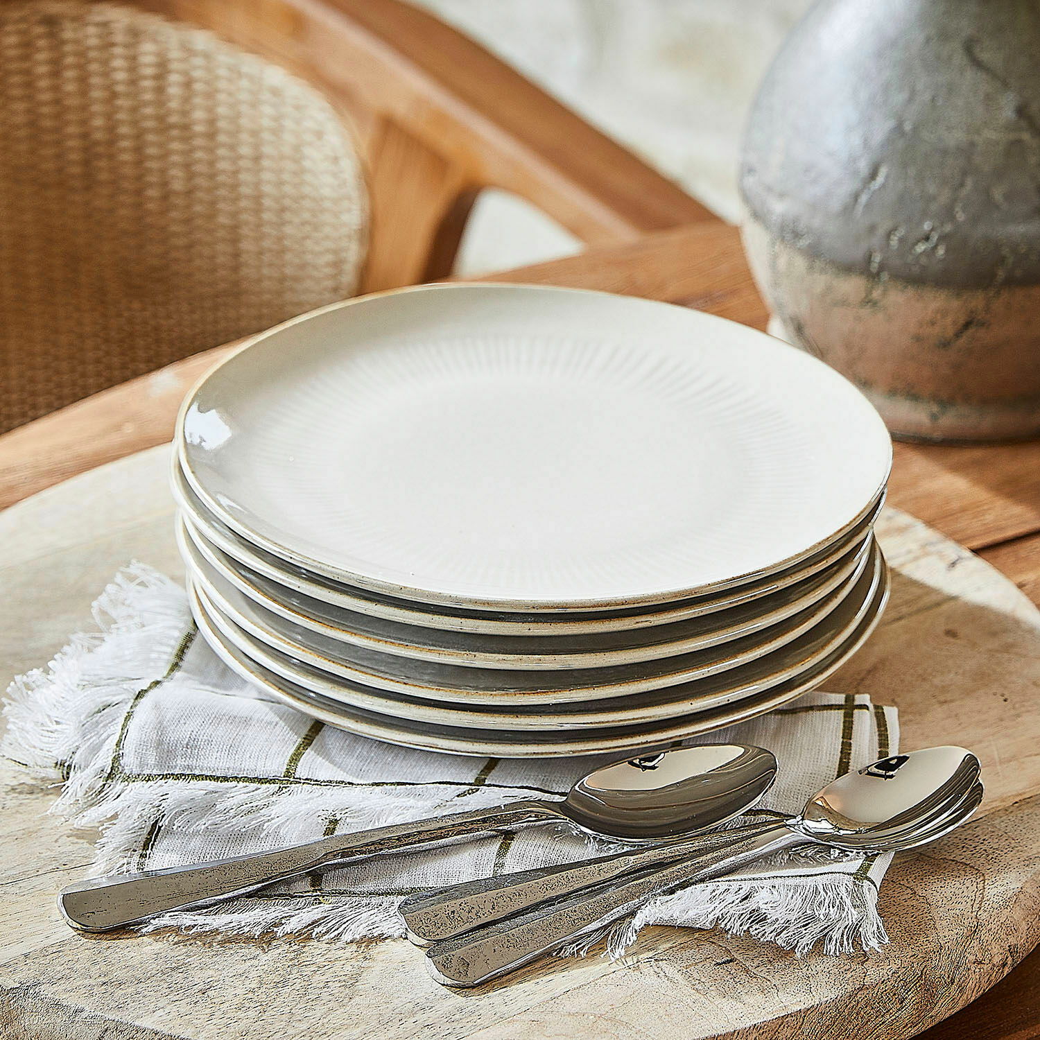Set de 6 platos de postre Périers Juego de seis platos de cerámica crema con diseño sutil y cucharas metálicas sobre servilleta de lino