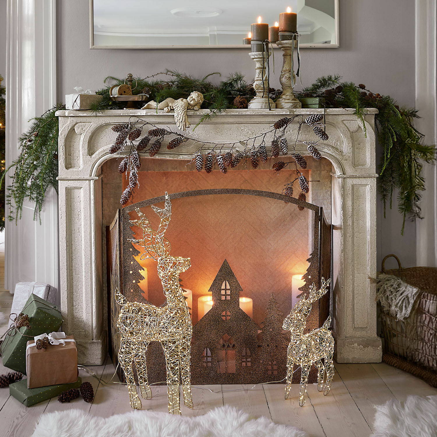 Consola de chimenea Woodcroft Chimenea decorativa de piedra blanca con renos iluminados y velas navideñas en sala acogedora