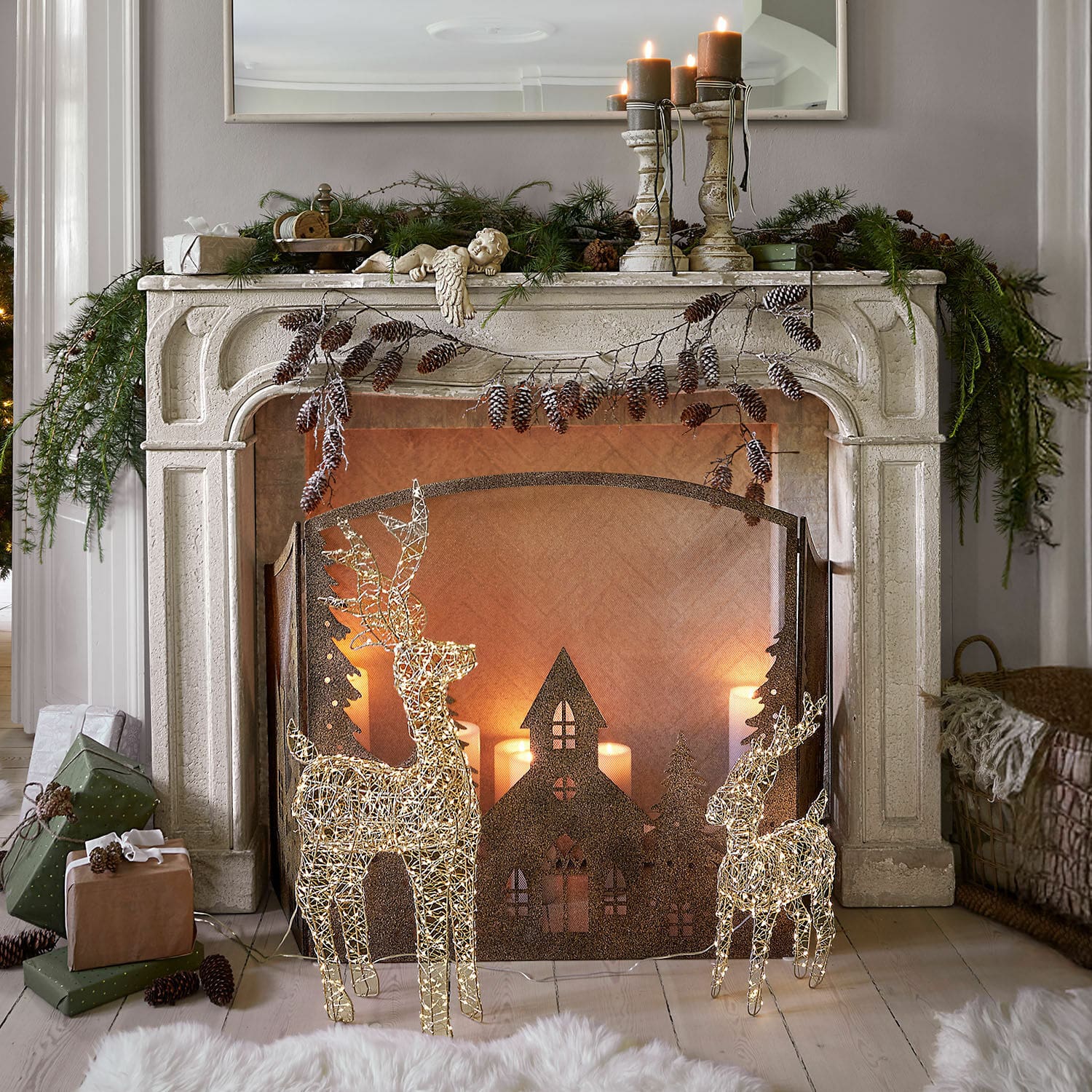 Consola de chimenea Woodcroft Chimenea decorativa de piedra blanca con renos iluminados y velas navideñas en sala acogedora