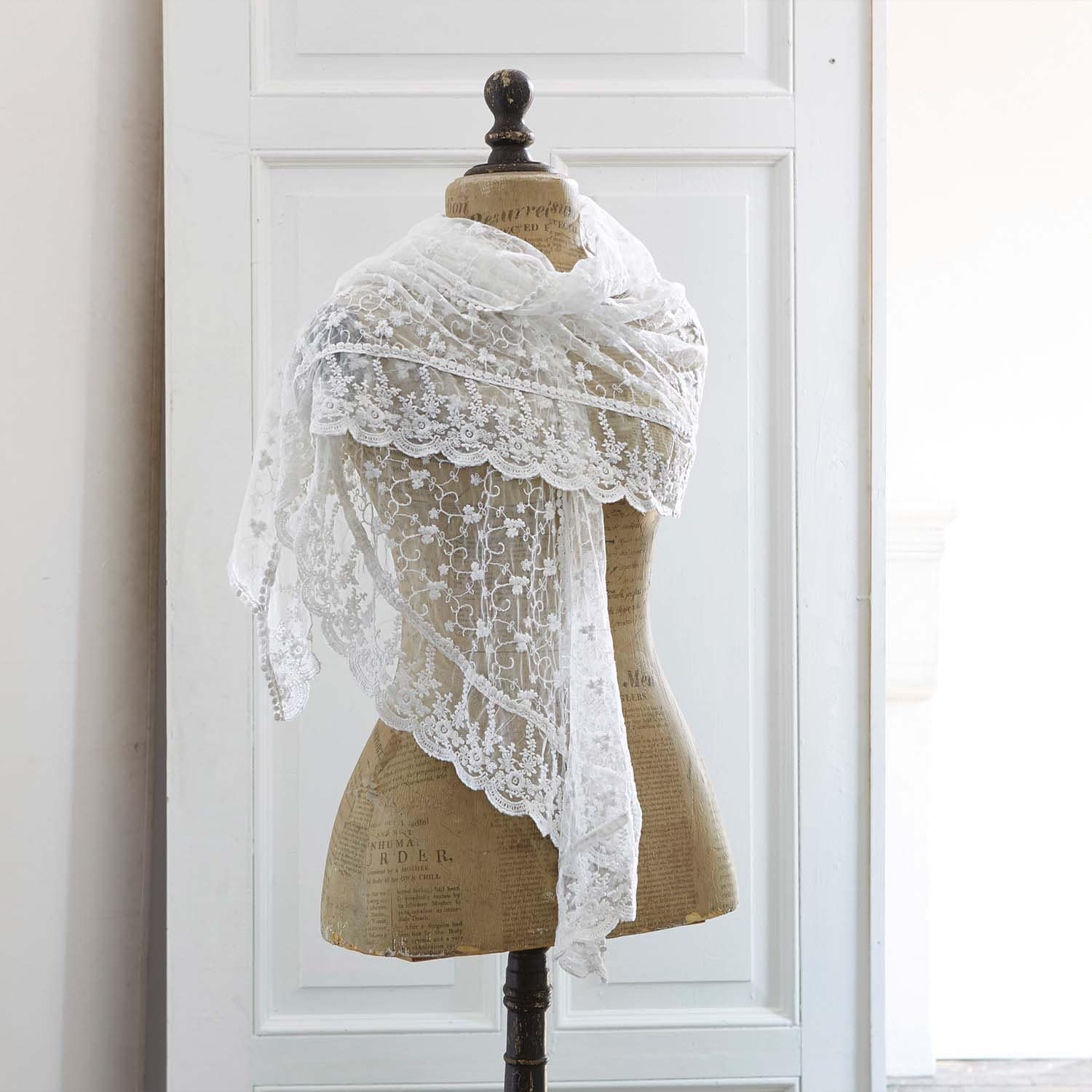 Chal blanco de encaje fino con diseño floral sobre maniquí, accesorio elegante para vestir