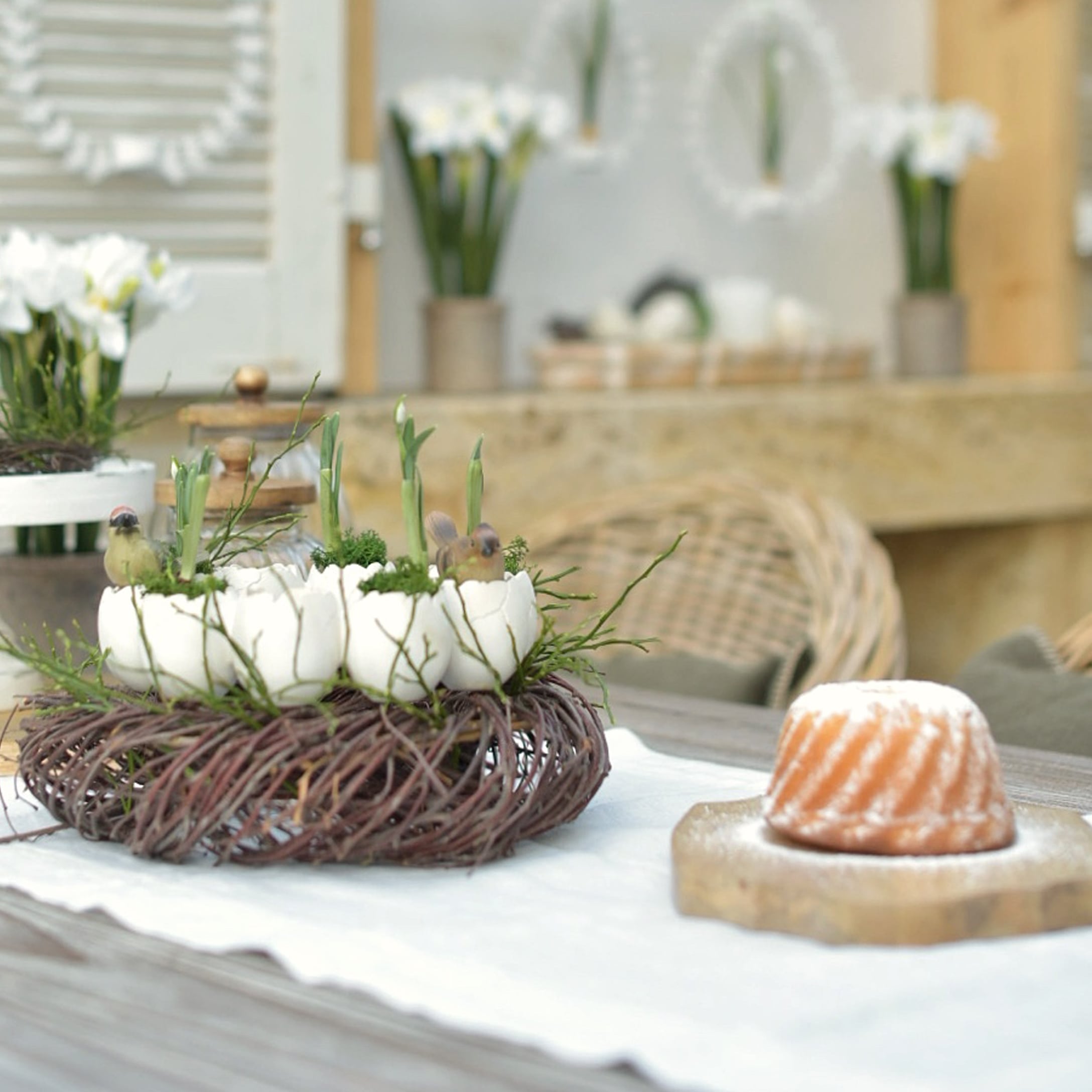 Corona decorativa de ramas naturales con cáscaras de huevo blancas y plantas verdes sobre la mesa