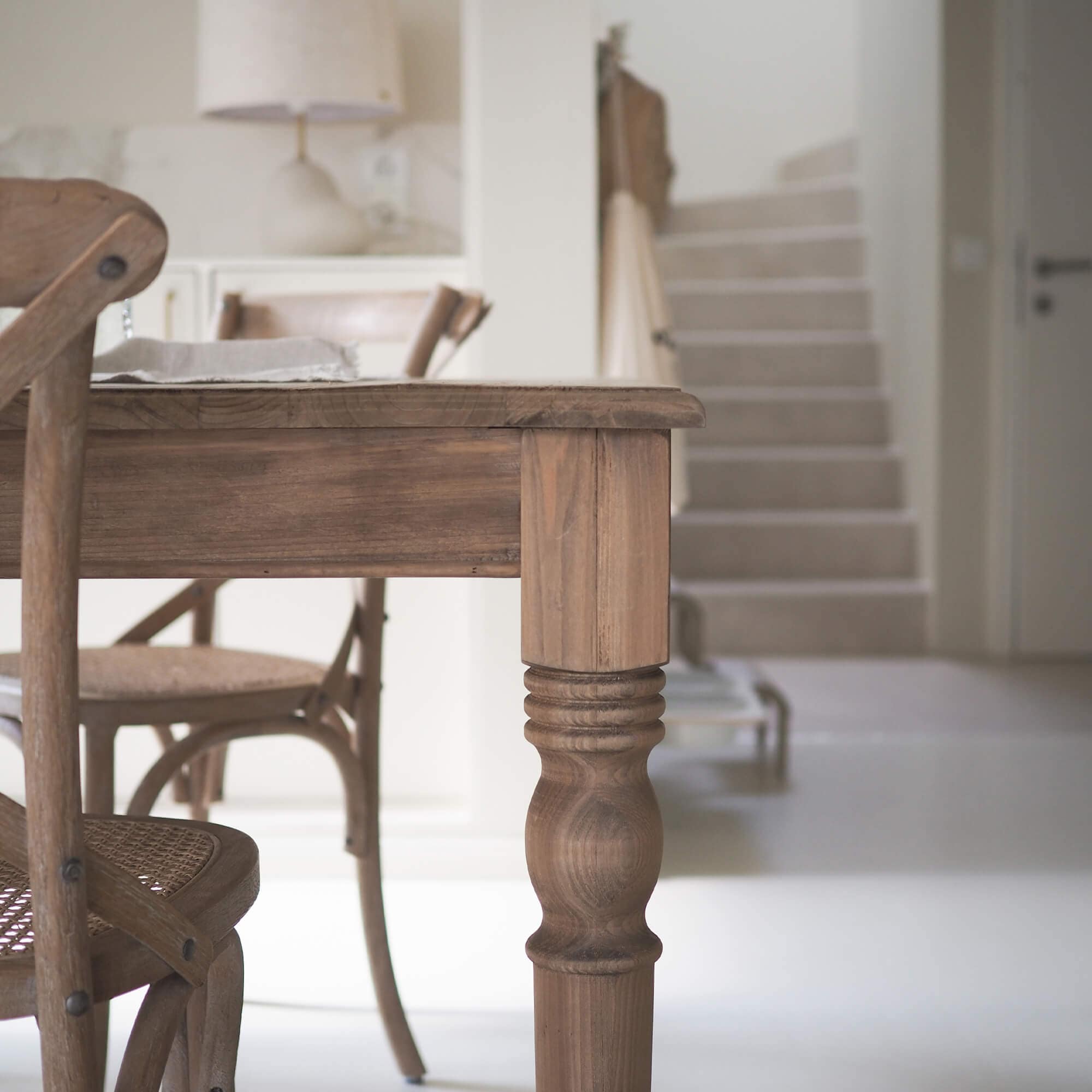 Mesa y sillas de madera en color natural en un interior moderno y luminoso con suelo blanco