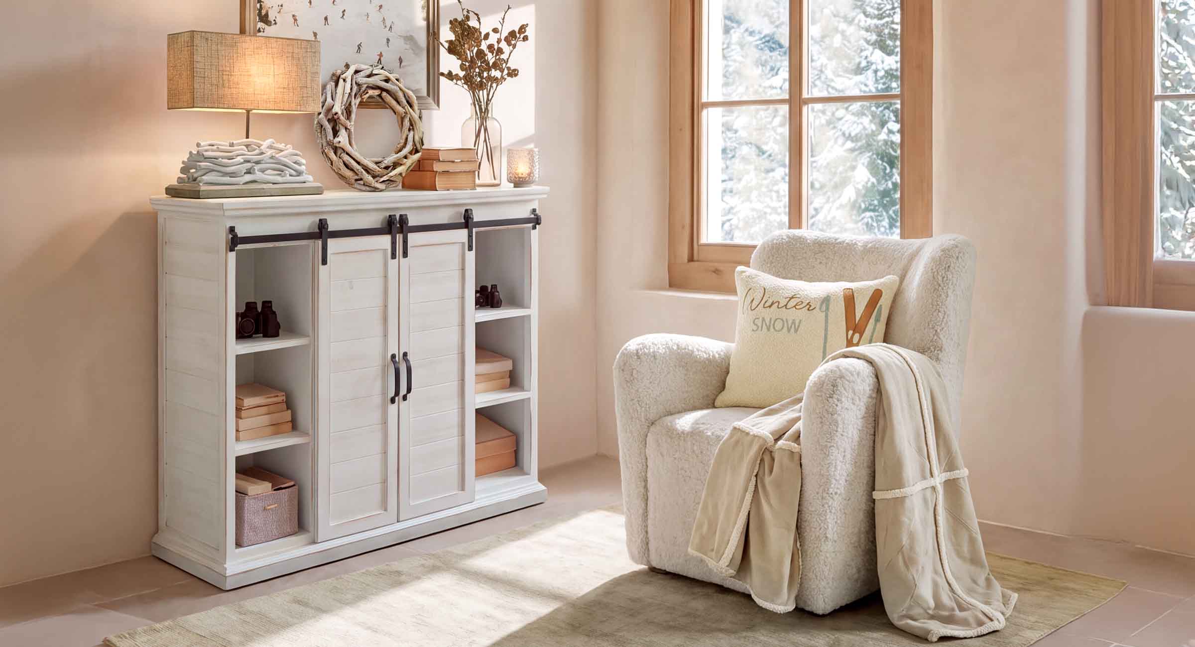 Rincón acogedor con sillón blanco de felpa y aparador de madera clara en habitación luminosa con vista invernal