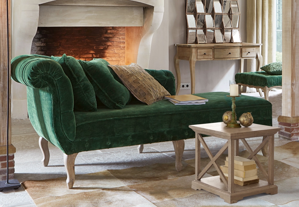 Sofá clásico verde de terciopelo con patas de madera en salón elegante con chimenea