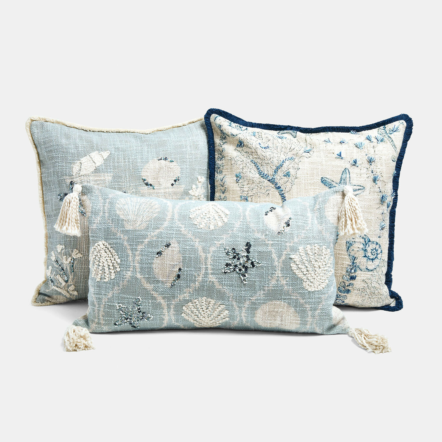 Set de 3 fundas de cojín Calerand Conjunto de tres cojines decorativos con motivos de conchas y estrellas de mar en tonos azul y crema