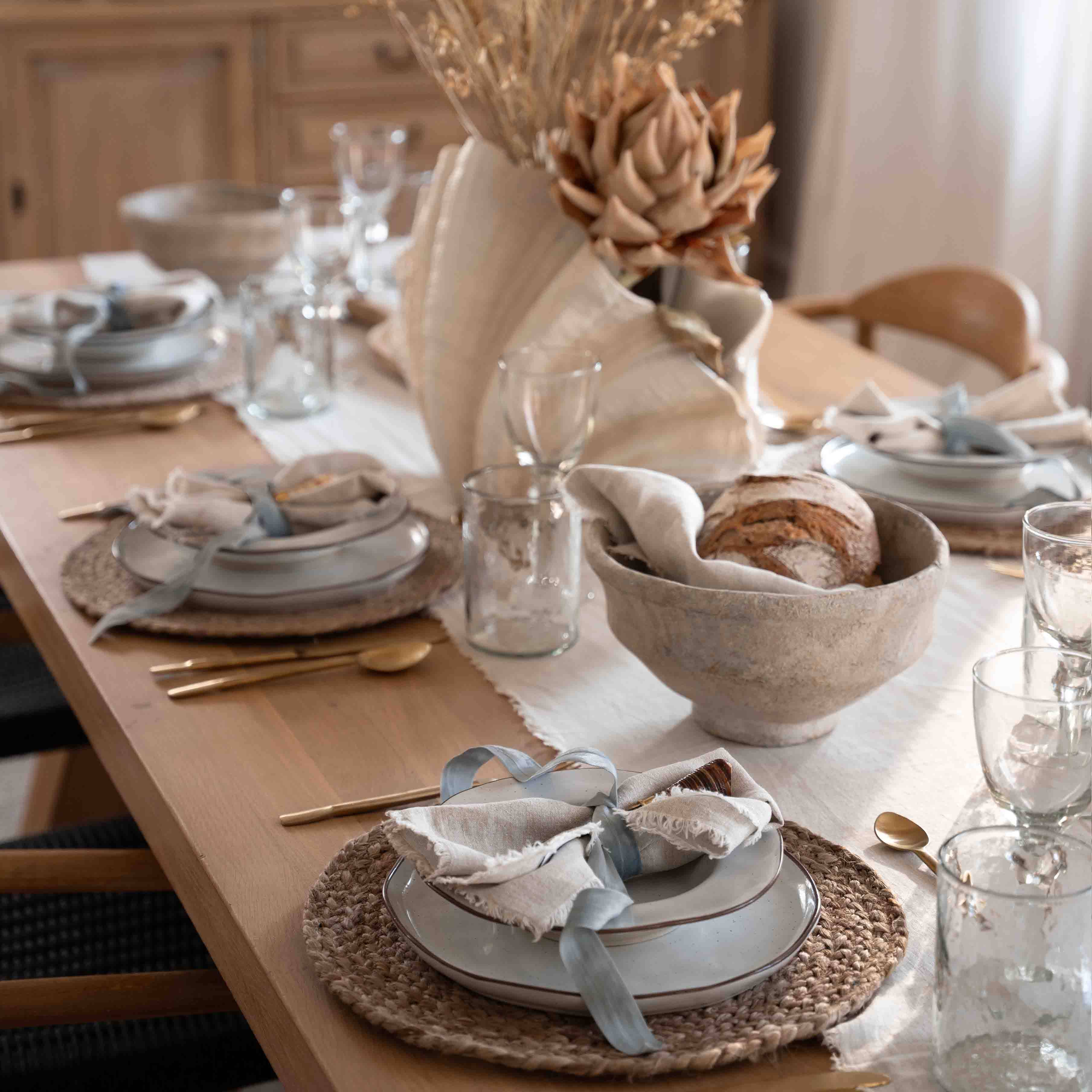 Decoración de mesa con concha natural y pan en un cuenco de lino sobre mesa de madera