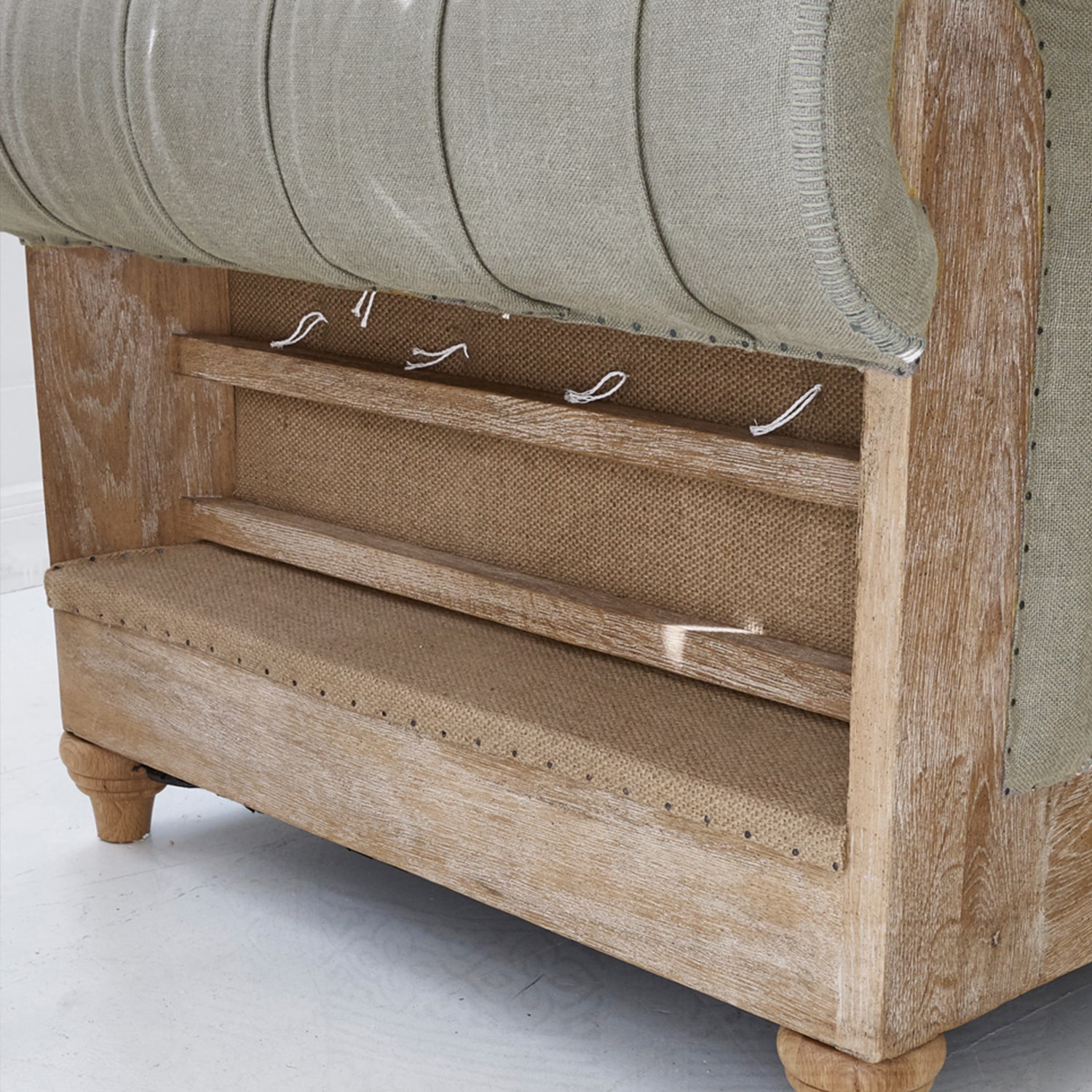 Sofá de madera clara y tela beige con estructura visible y detalles de acabado