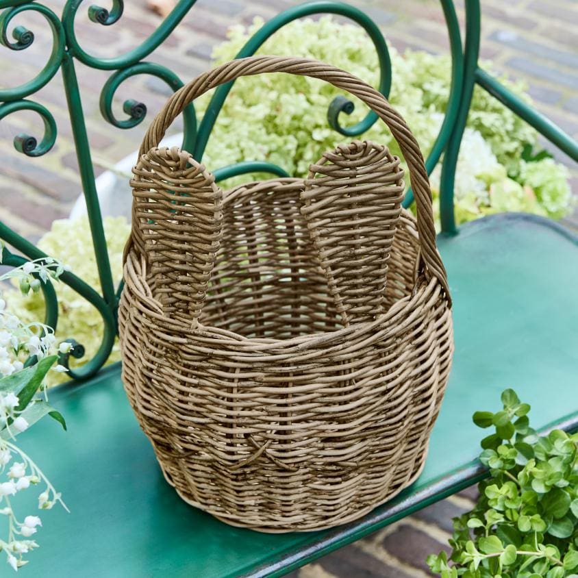 Cesta de mimbre natural con asas en banco verde, cesta decorativa para jardín o exterior