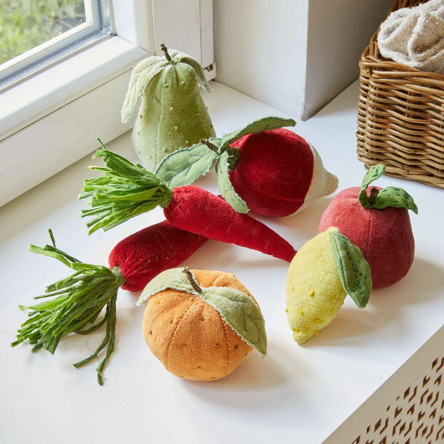 Set de 7 frutas y verduras de tela Mivola Conjunto de frutas y verduras de peluche en varios colores sobre un alféizar blanco, decoración textil