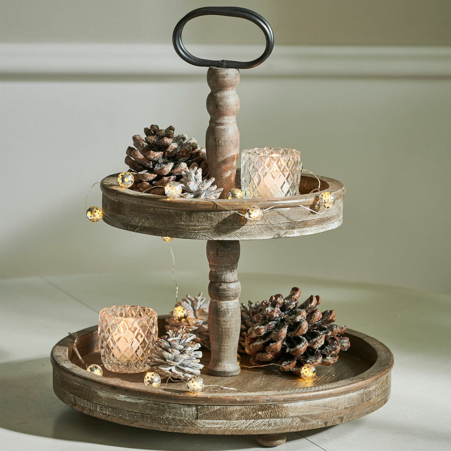 Bandeja de madera de dos niveles decorada con piñas y velas LED para ambiente acogedor
