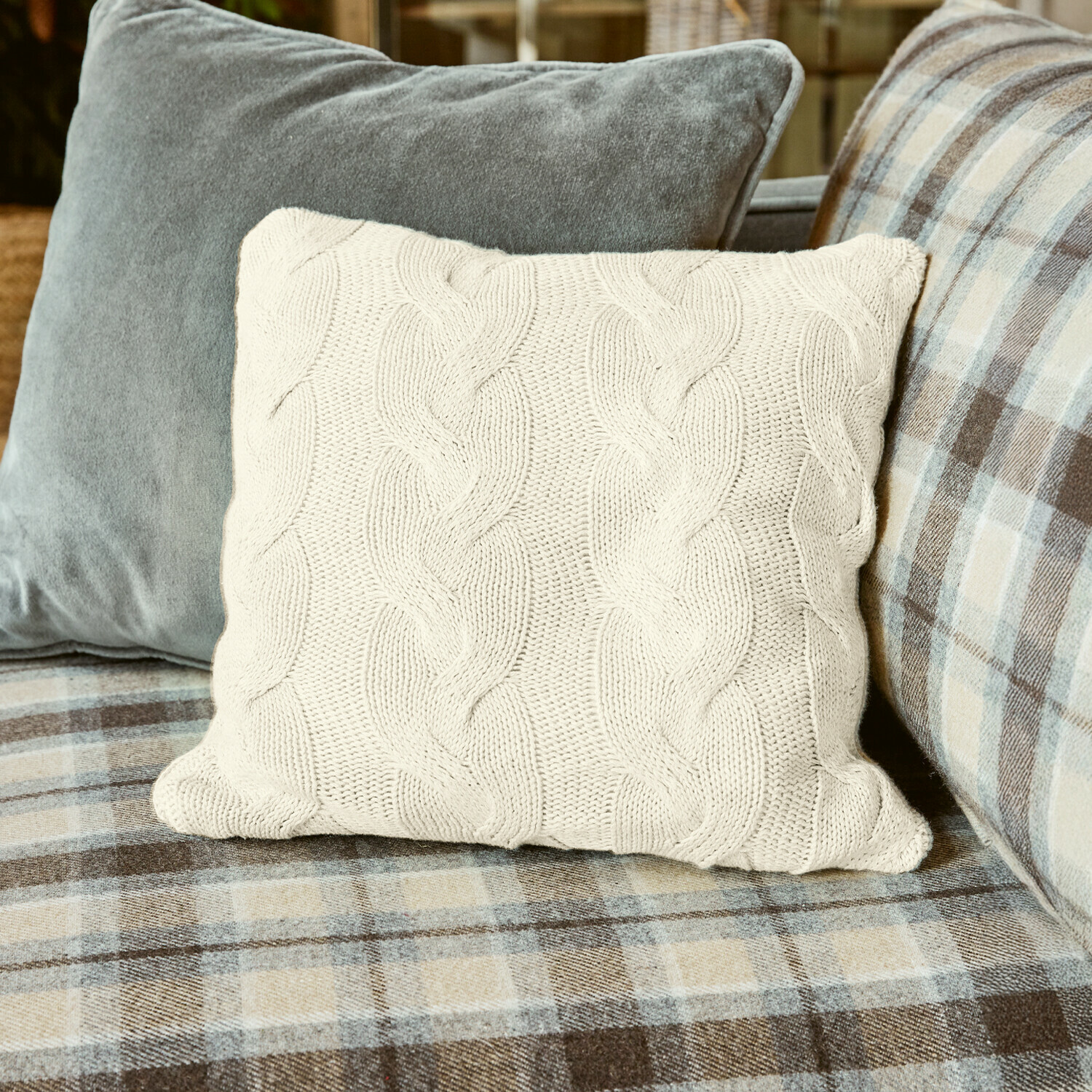 Funda de cojín Arnhem Cojín beige de punto con diseño trenzado sobre sofá a cuadros, decoración acogedora