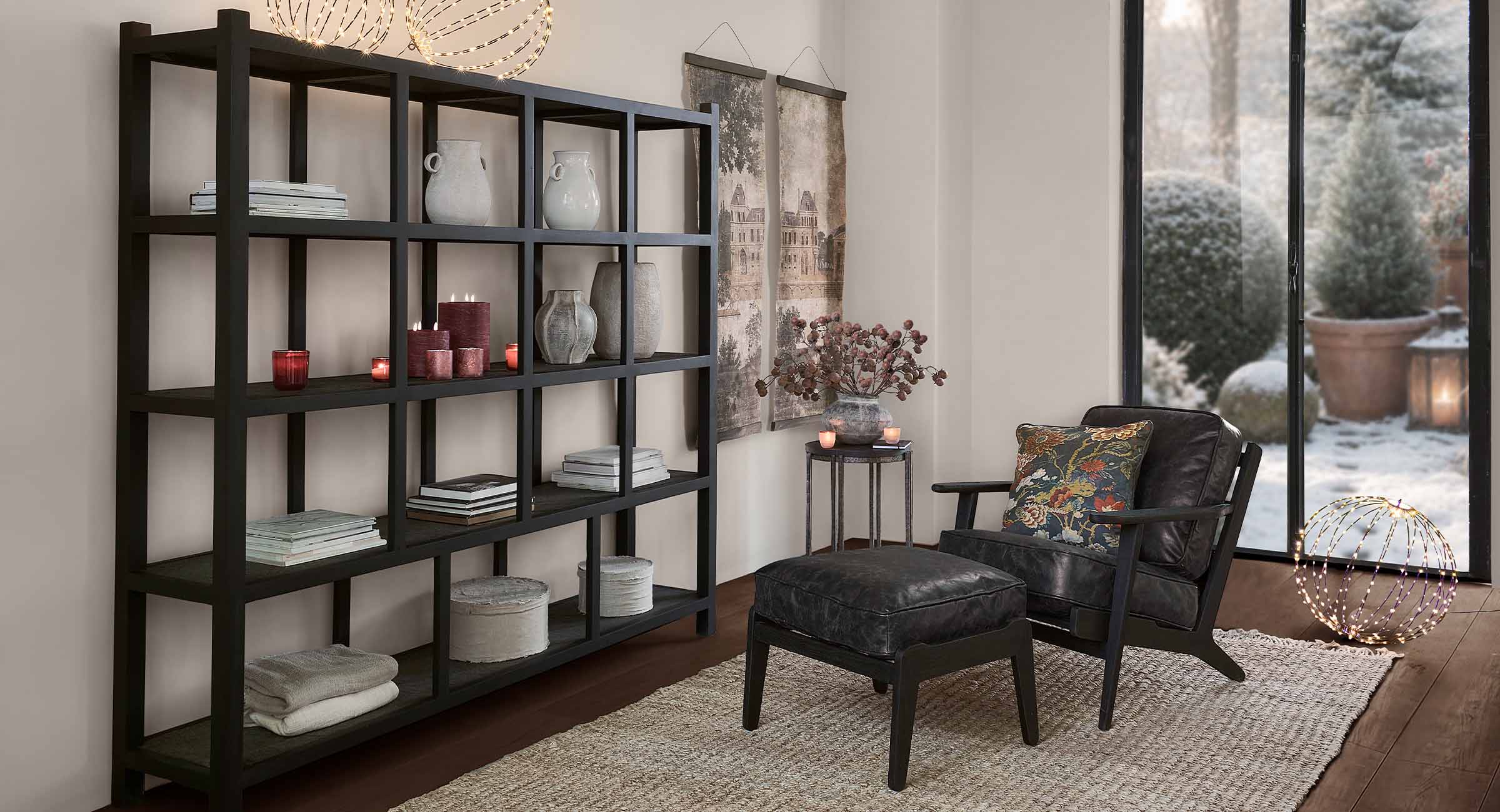 Estantería negra de madera con decoraciones en salón acogedor con vista a jardín de invierno nevado