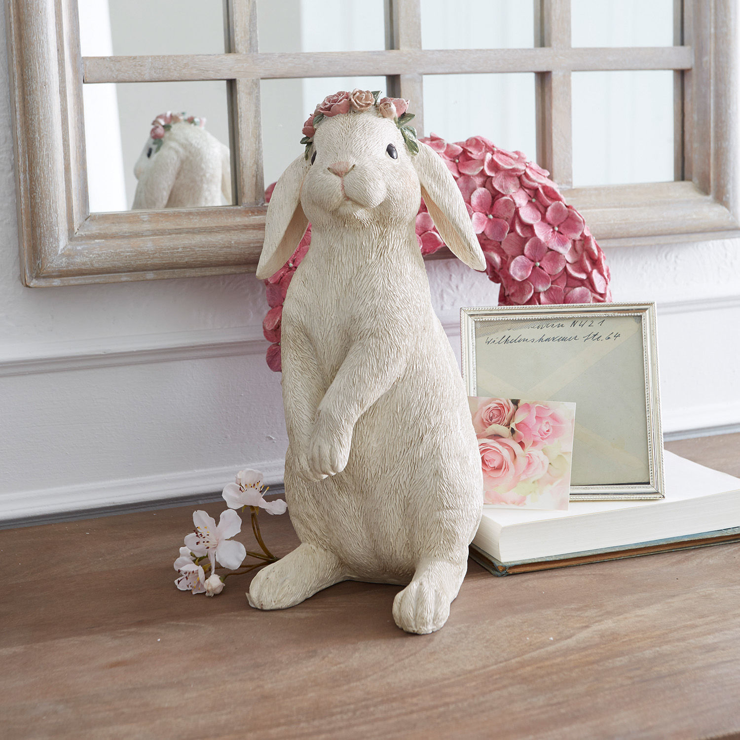 Liebre Sweety Figura de conejo color crema con corona de flores rosas sobre mesa decorada