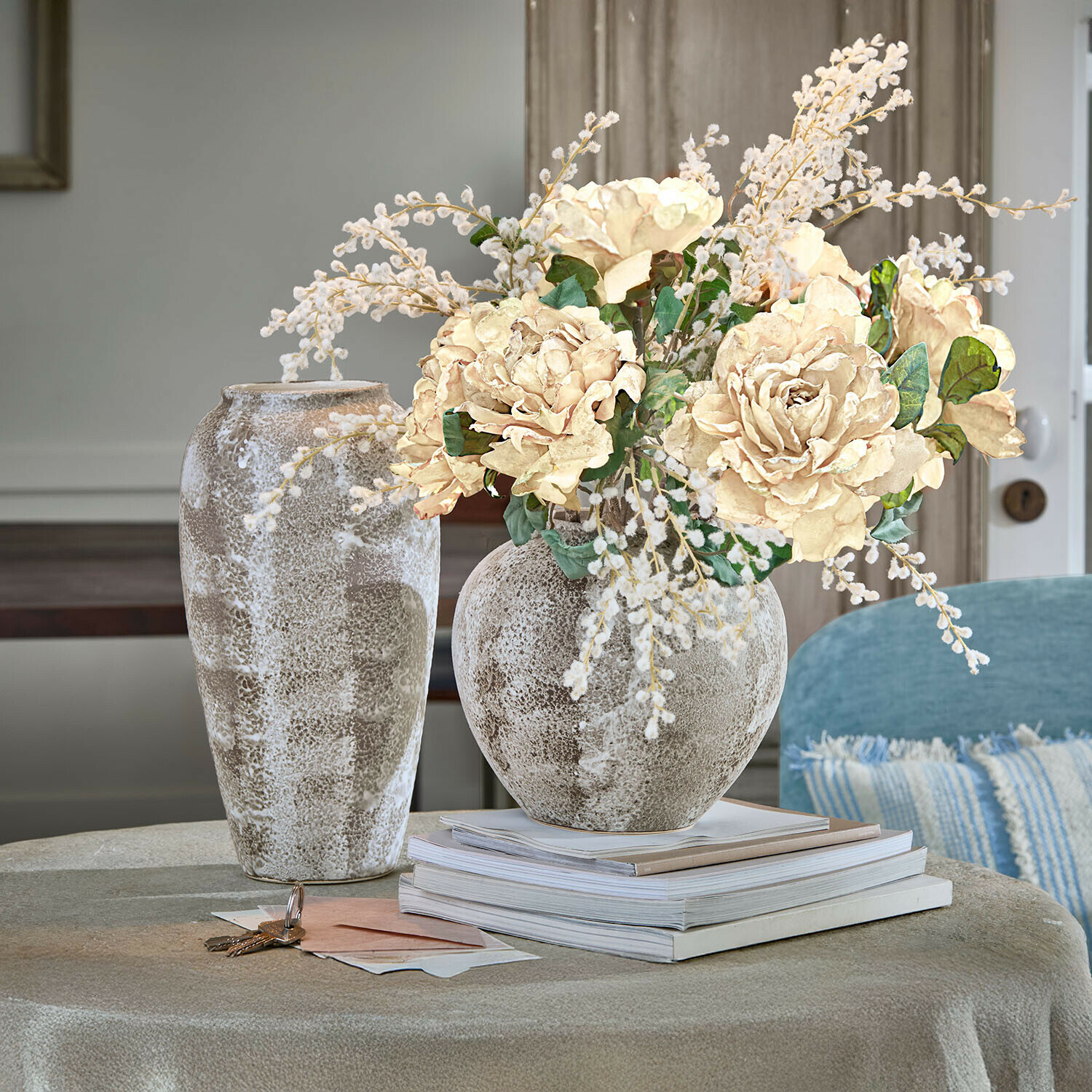 Set de 2 jarrones Ciel d'Opale Jarrón decorativo de cerámica beige y marrón con ramo de flores crema sobre mesa con libros apilados