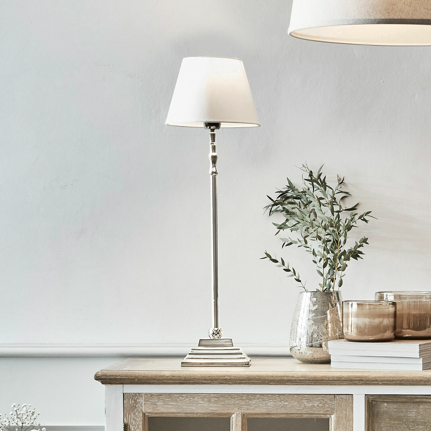 Lámpara de mesa Mayfair Lámpara de mesa elegante con pantalla blanca y base metálica sobre mueble de madera, decoración interior