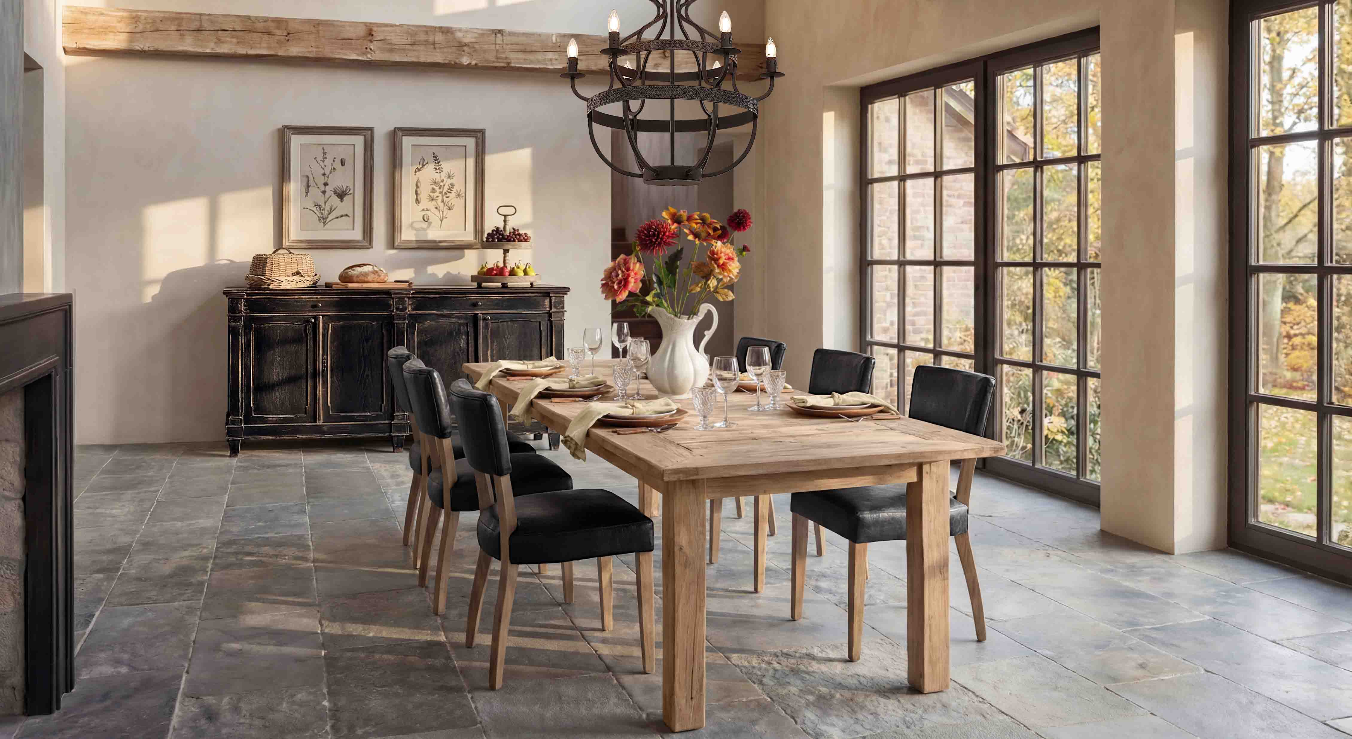Comedor con mesa de madera clara y sillas negras, luz natural a través de grandes ventanas
