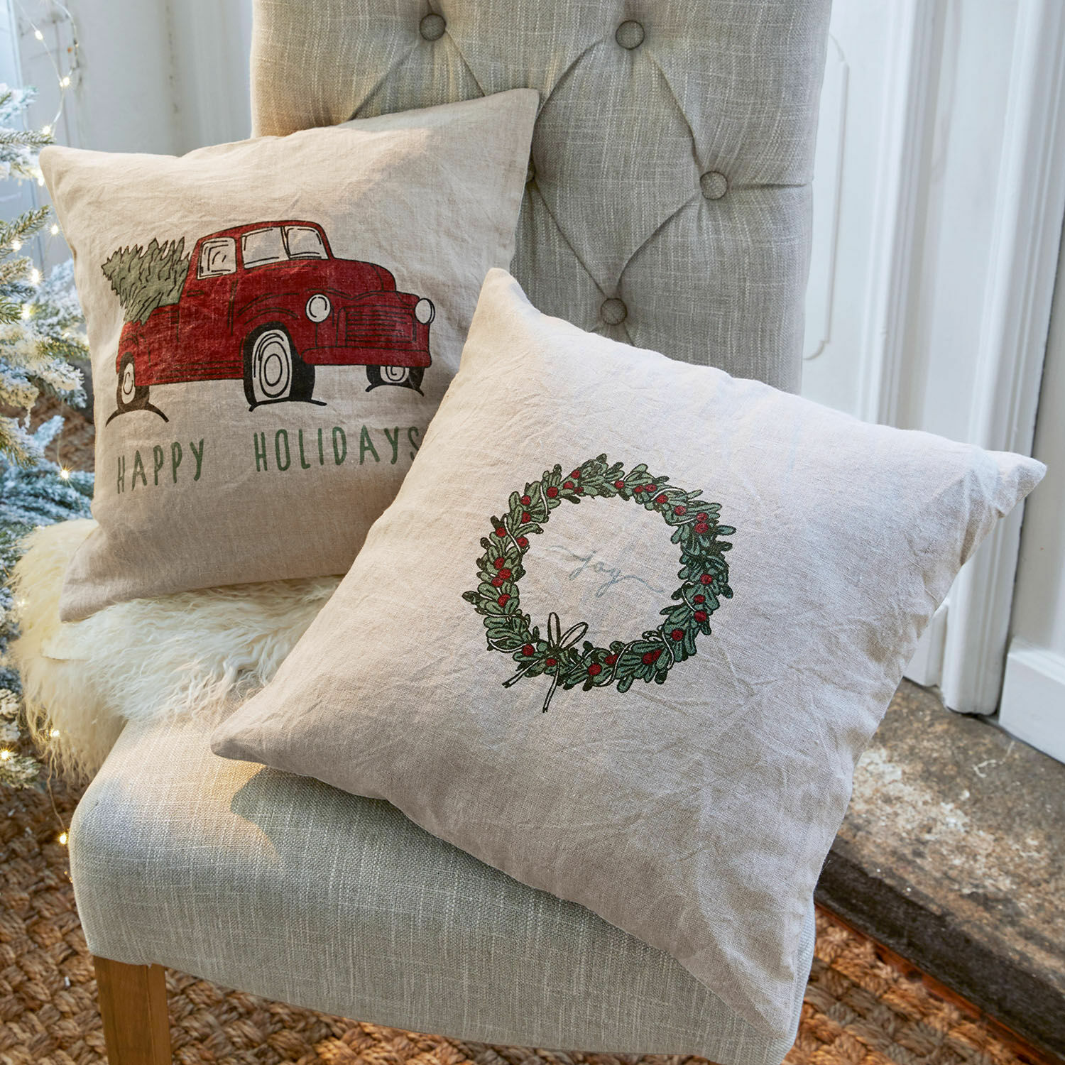 Set de 2 fundas de cojín Camon Cojines decorativos de lino con motivos navideños en colores naturales sobre silla gris