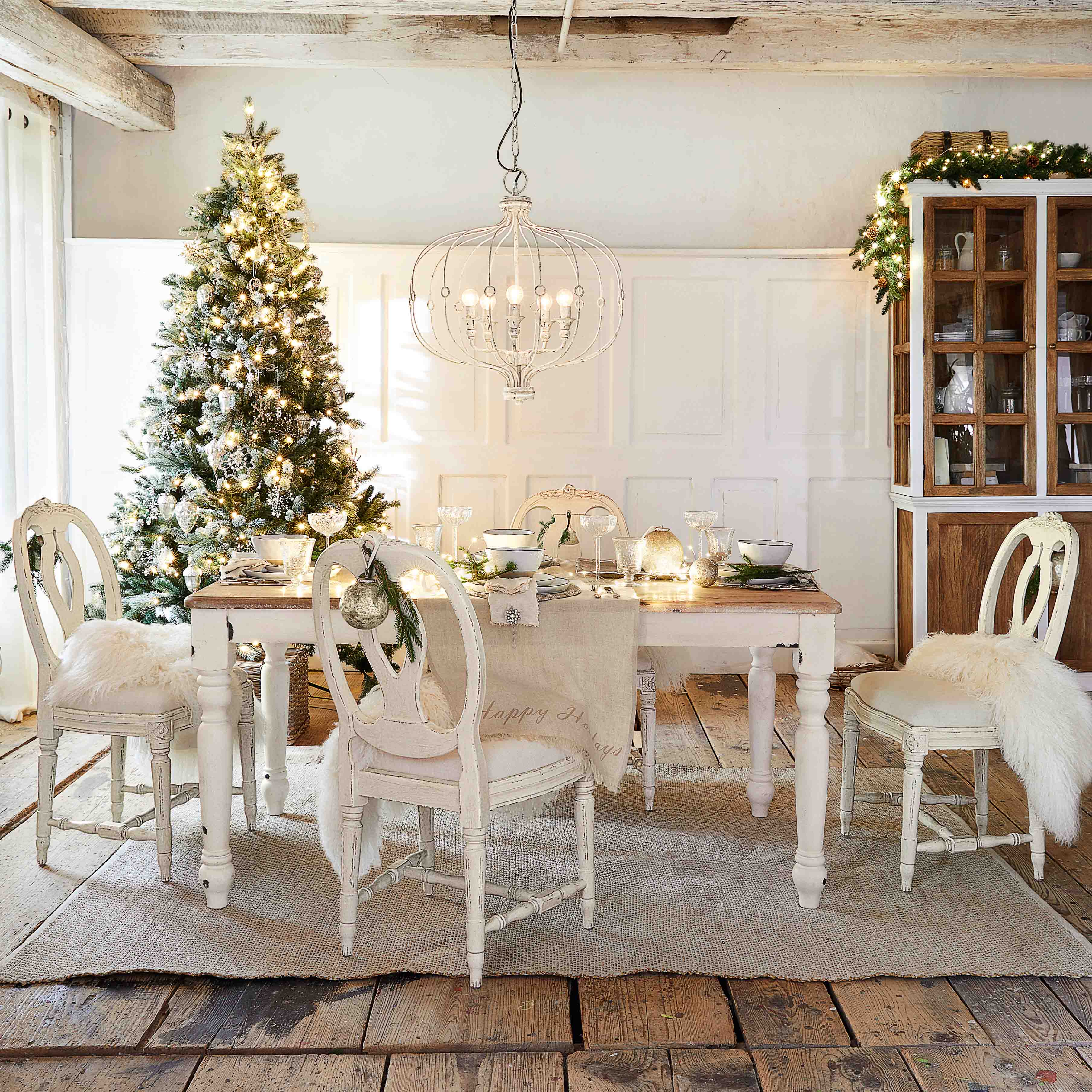 Comedor rústico con mesa y sillas blancas de madera, decorado para Navidad con árbol y lámpara colgante