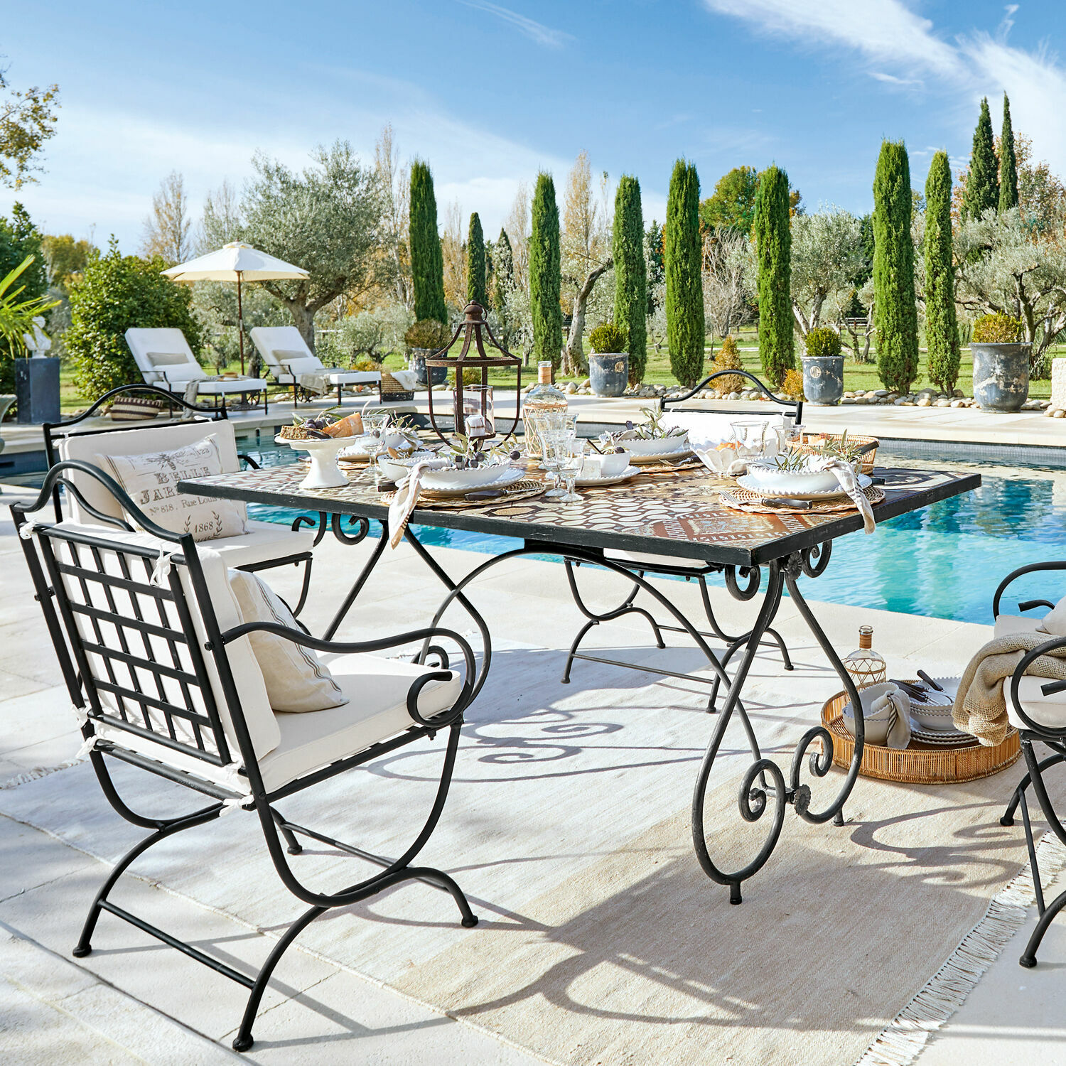 Mesa Grainville Conjunto de muebles de jardín de metal con mesa de mosaico junto a la piscina en un día soleado