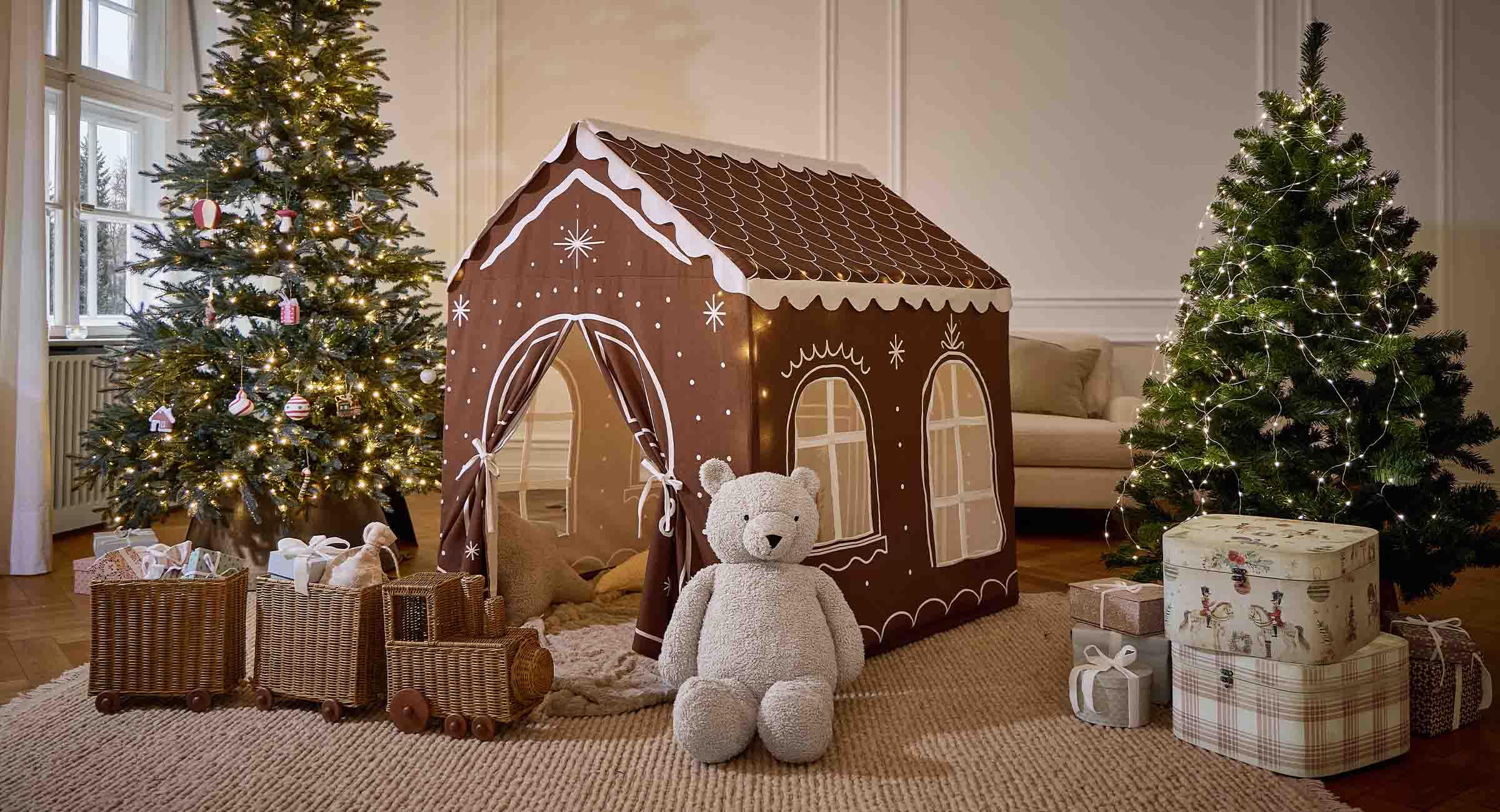 Tienda infantil marrón con forma de casa de jengibre con dibujos blancos, oso de peluche y decoración navideña