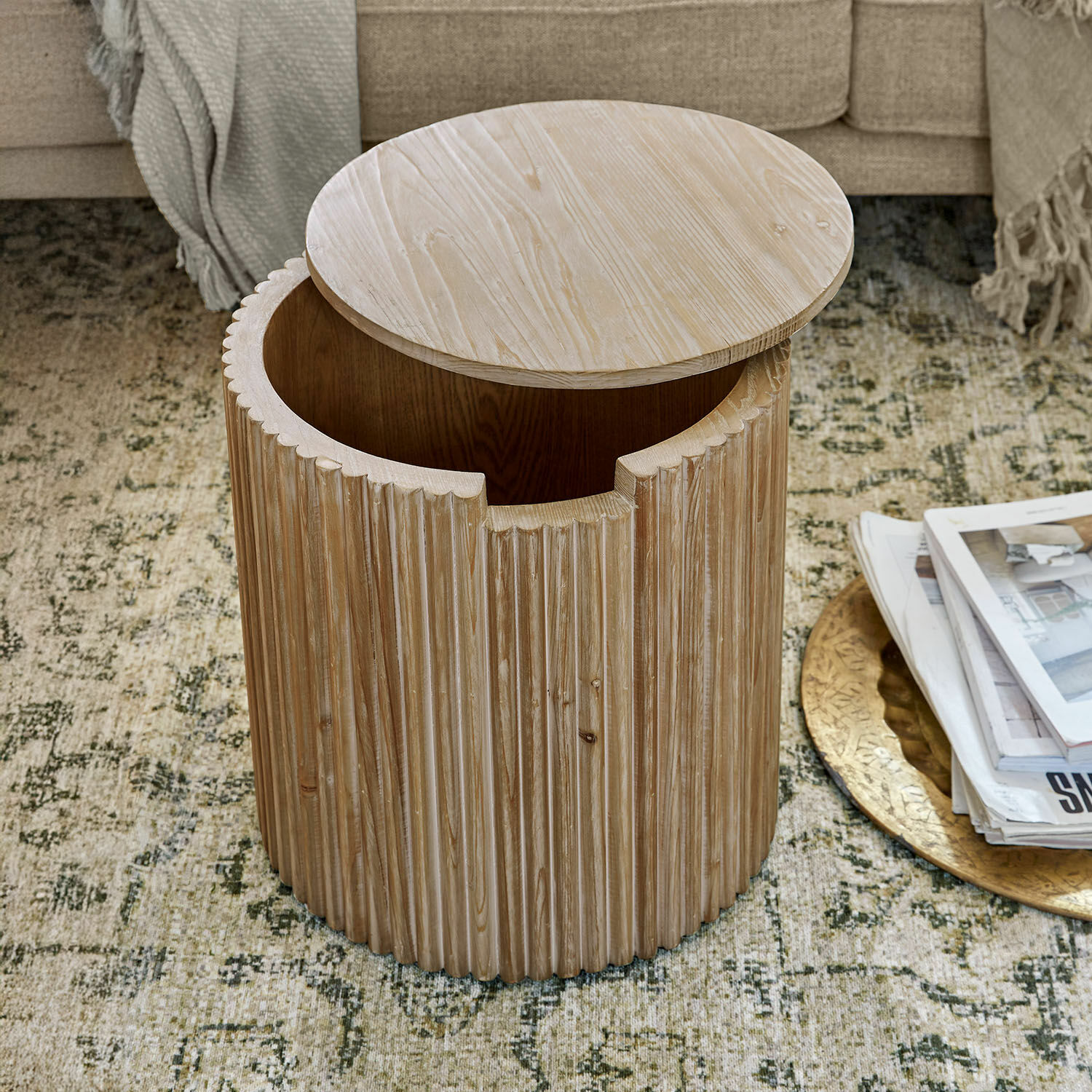Mesa auxiliar redonda de madera clara con superficie acanalada y espacio de almacenamiento práctico