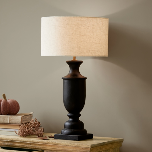 Lámpara de mesa de cerámica negra con pantalla beige sobre mesa de madera, decoración interior