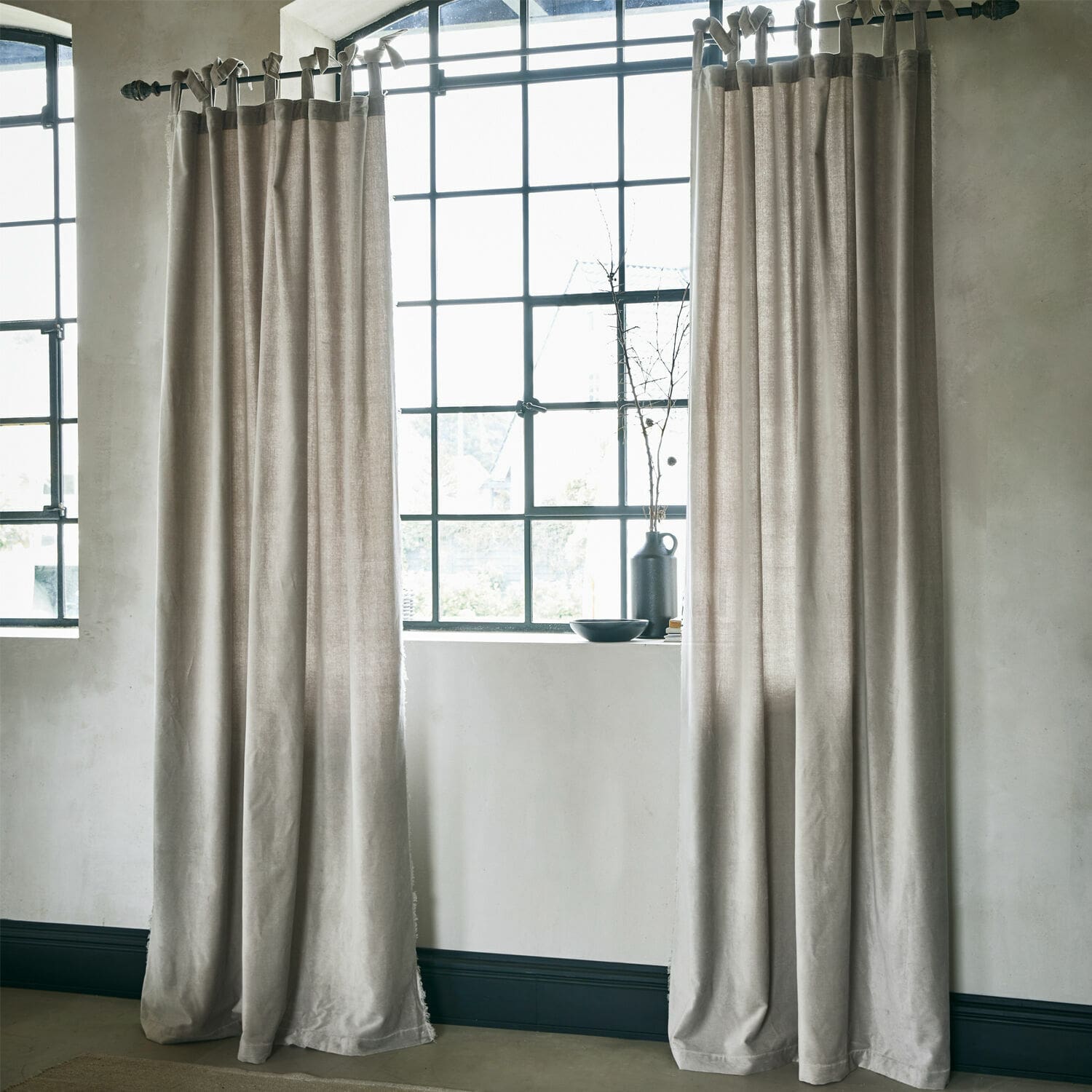 Cortina Bagujo Cortinas beige de tela natural junto a una ventana grande, decoración interior elegante y suave.