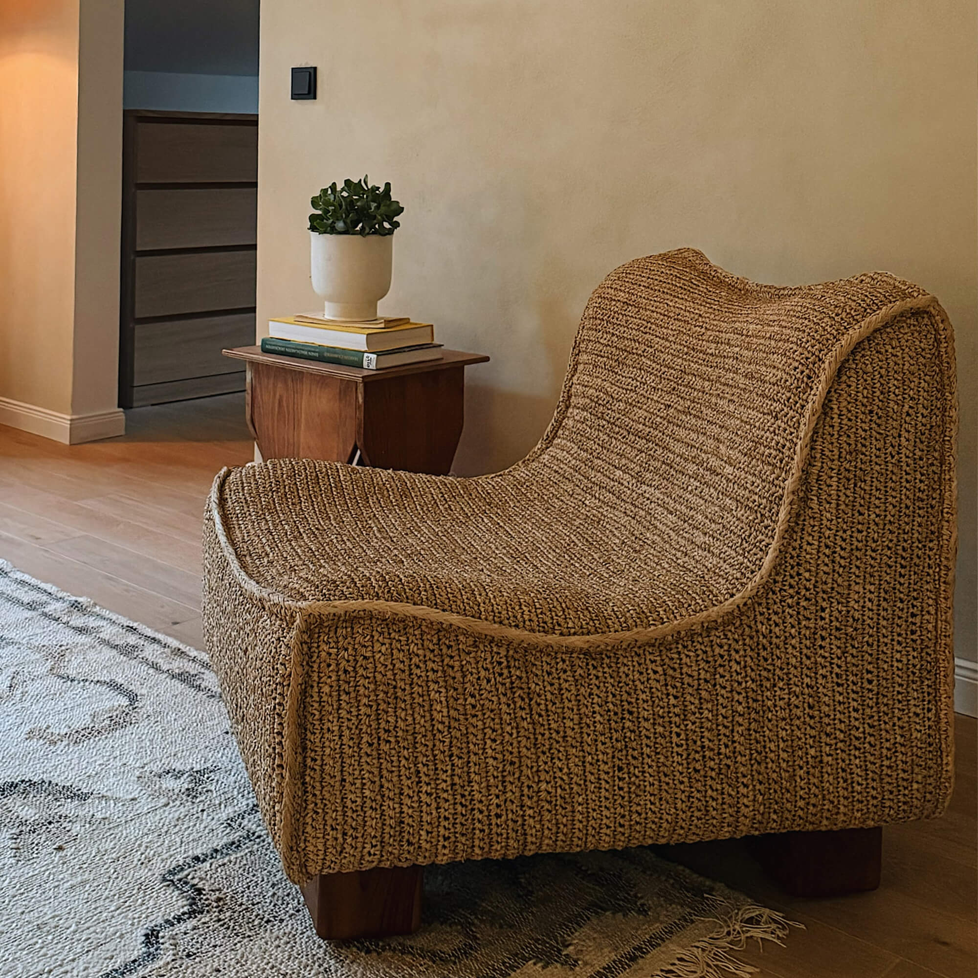 Sillón marrón de material trenzado con patas de madera en sala acogedora