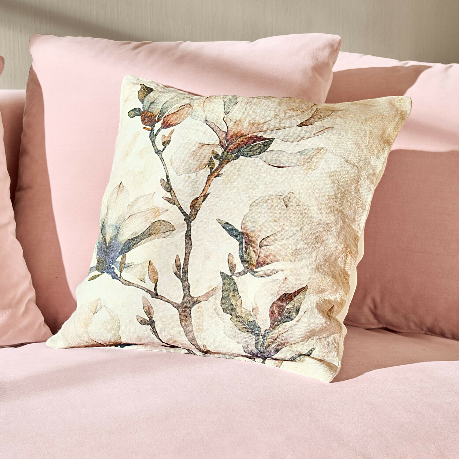 Cojín de lino con estampado floral sobre sofá rosa, decoración suave y elegante para salón