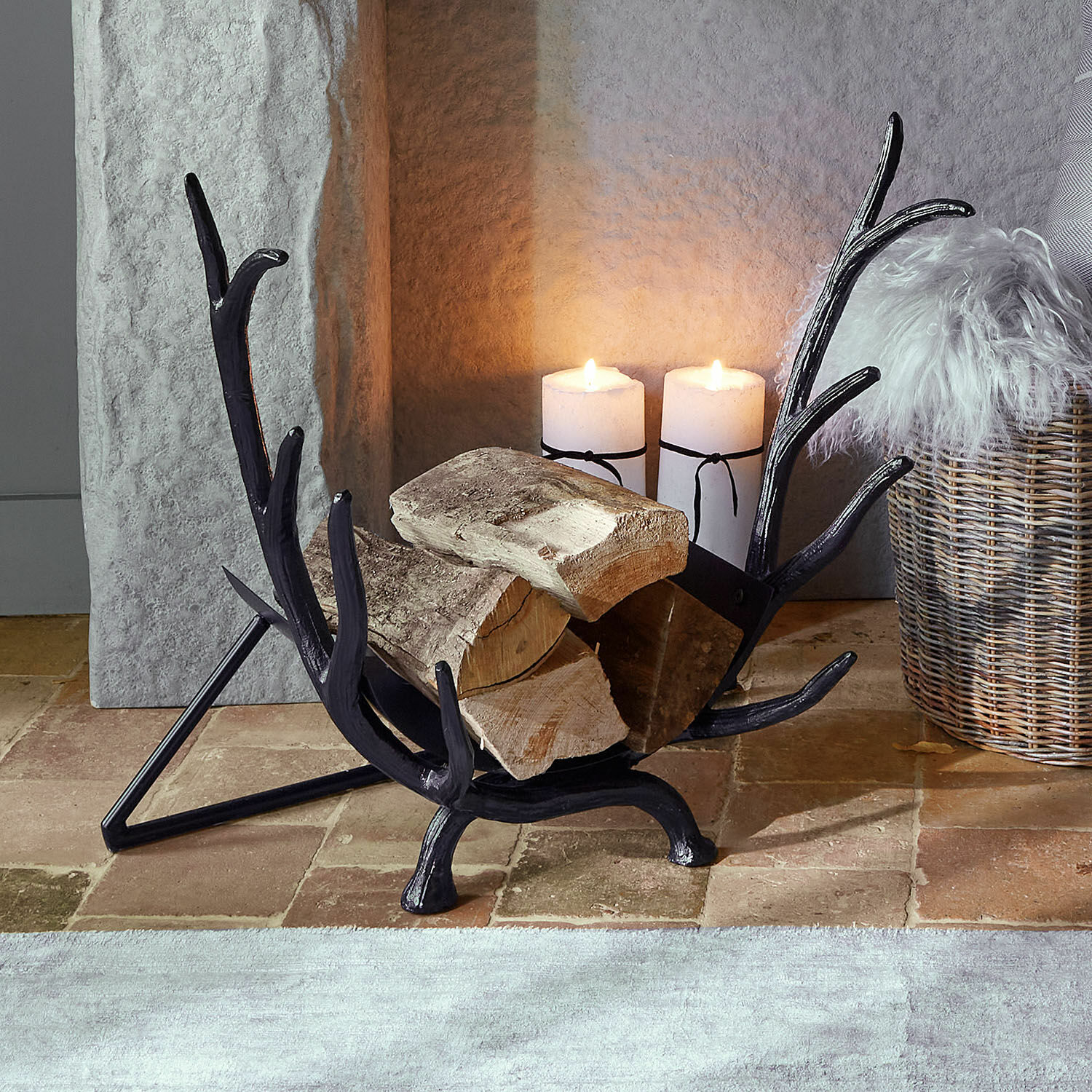 Soporte para leña Soreva Soporte para leña de metal negro con forma de astas de ciervo con troncos y velas encendidas