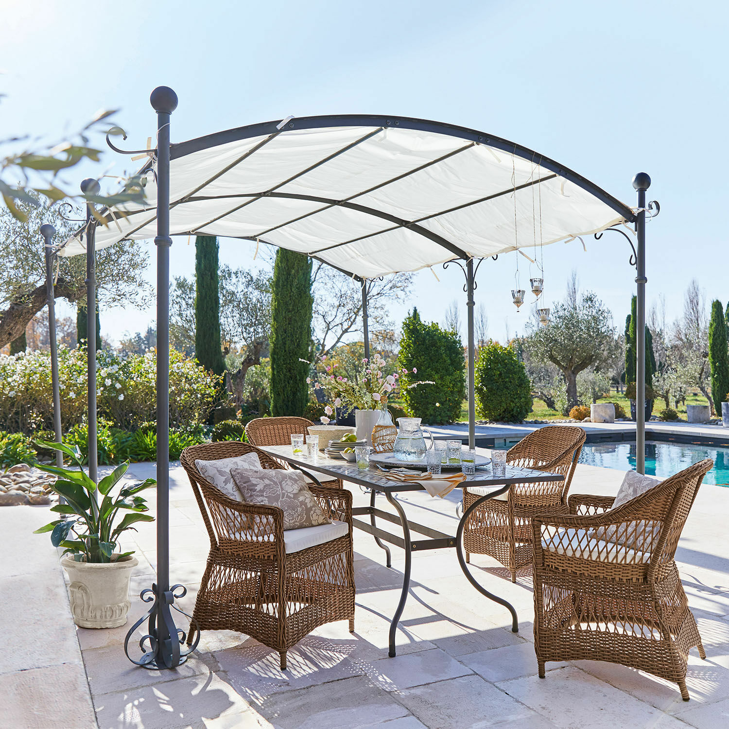 Pérgola Yarl Conjunto de muebles de jardín de ratán marrón bajo un pabellón metálico blanco junto a la piscina
