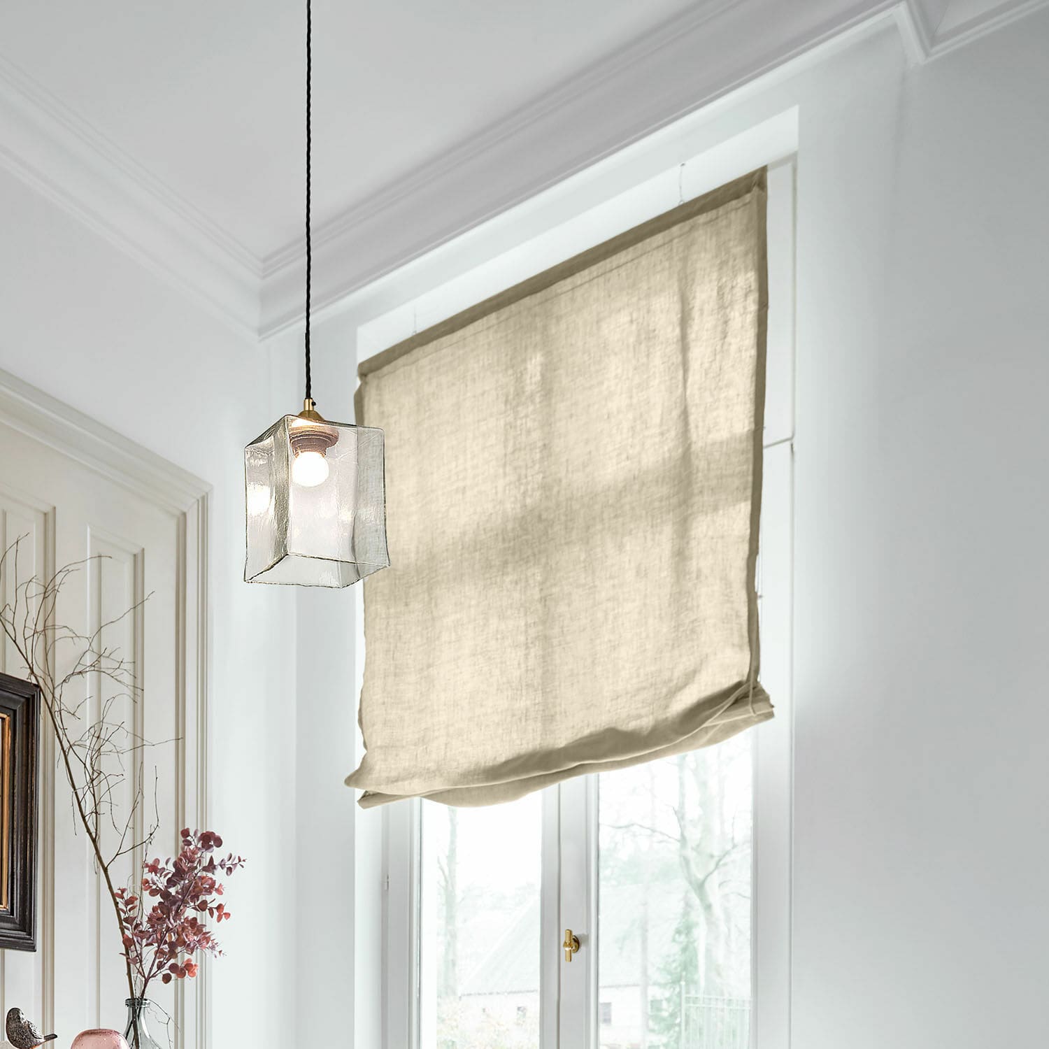 Estor plegable Lunavaux Estor romano beige de lino en habitación luminosa con lámpara colgante y ventana