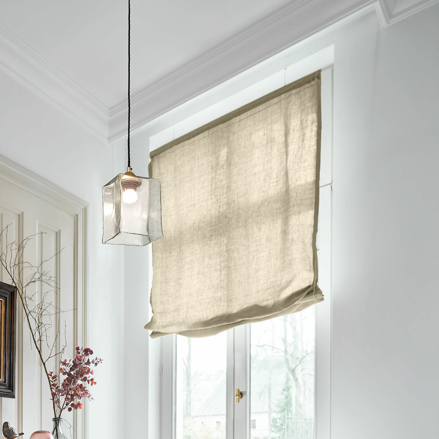 Estor plegable Lunavaux Estor romano beige de lino en habitación luminosa con lámpara colgante y ventana