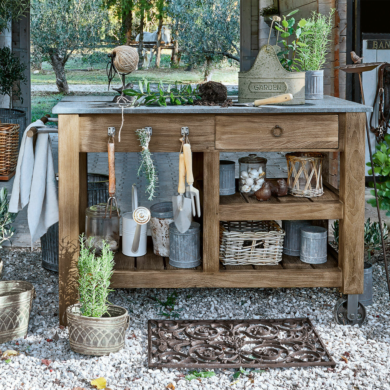 Mesa de jardinería Ellenton Mesa de jardín de madera con herramientas y macetas sobre grava en entorno natural