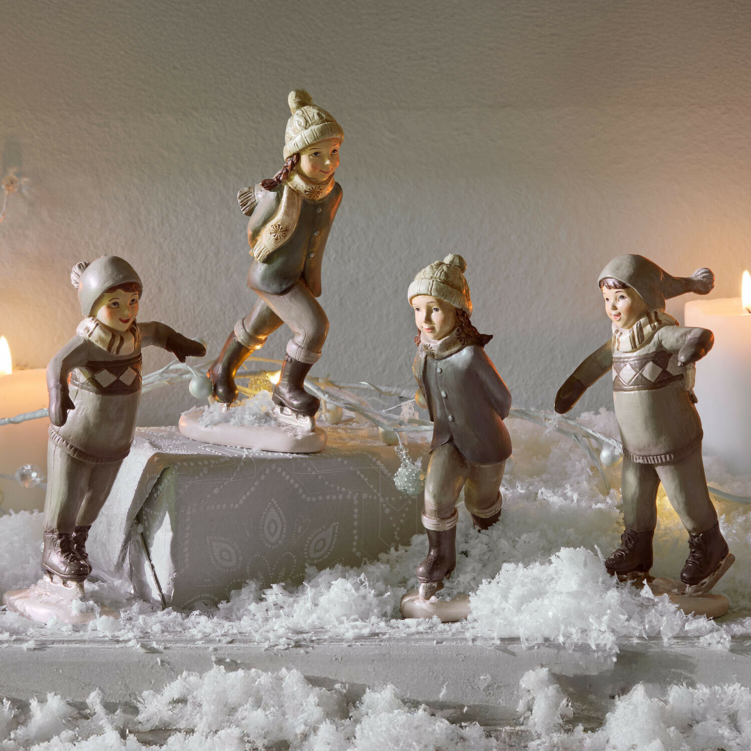 Set de 4 figuras Mériot Figuras de cerámica de niños patinando en tonos beige y gris sobre mesa decorada con nieve artificial