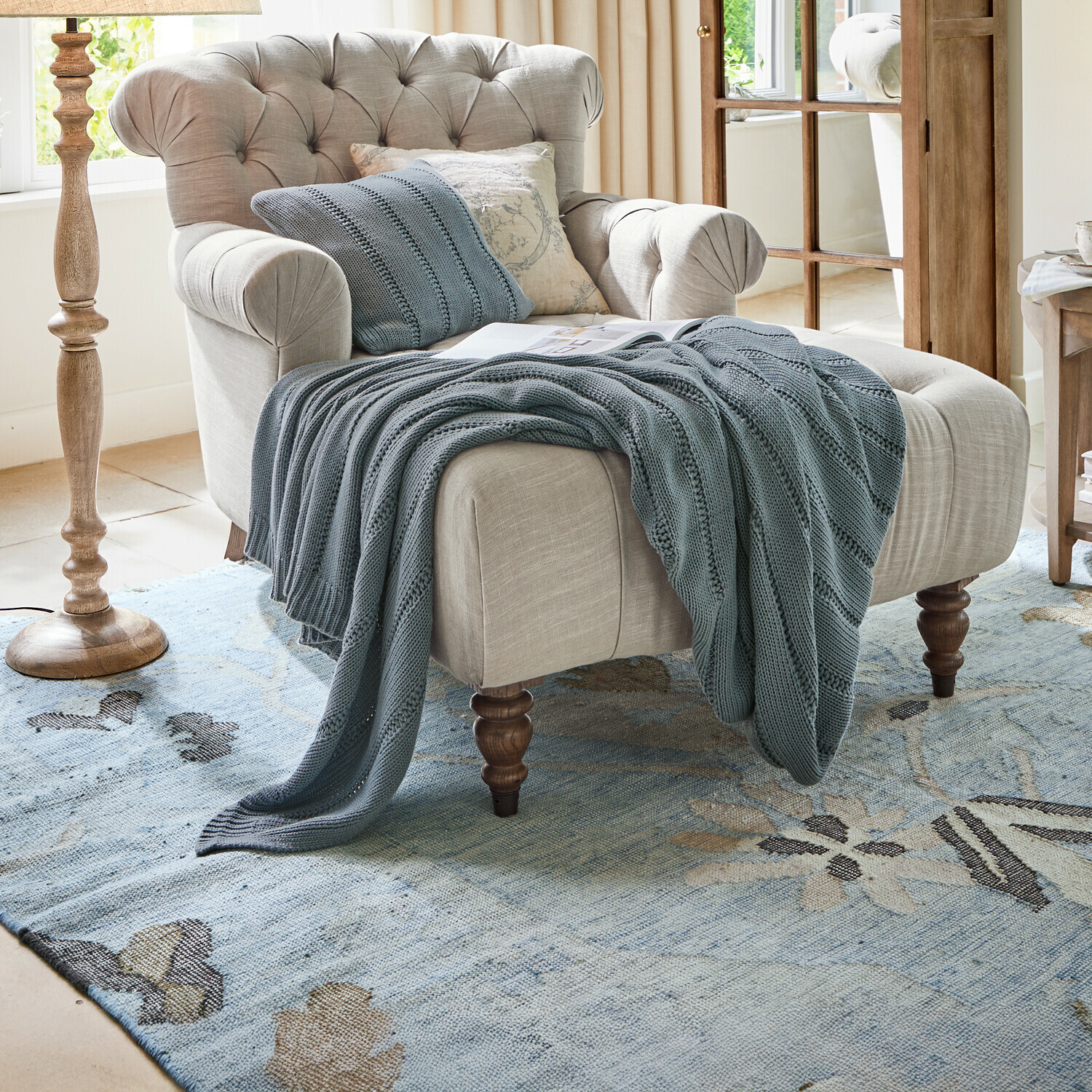 Plaid Lémeré Sillón beige de tela con respaldo capitoné y manta de punto azul en sala de estar